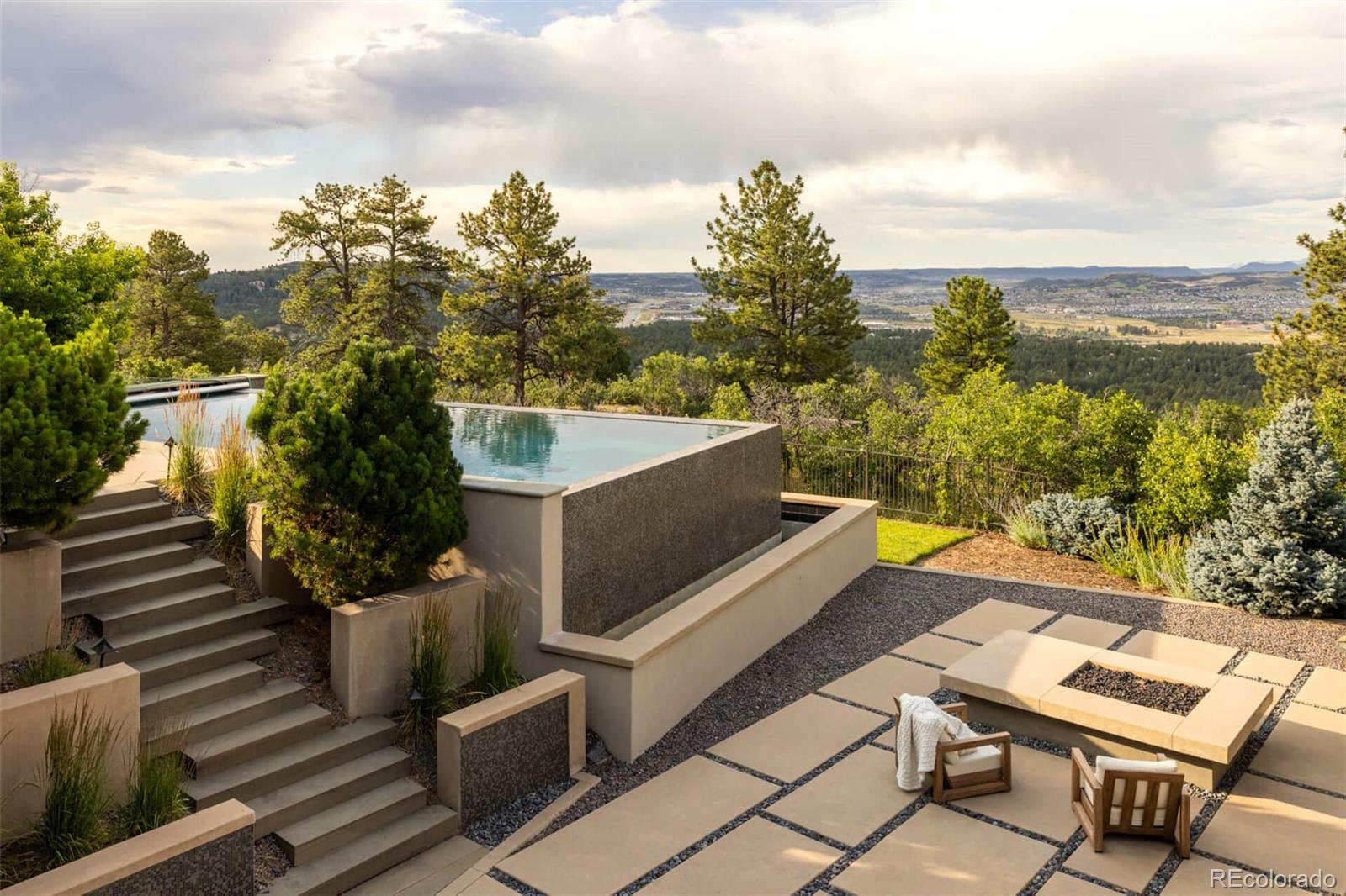 Perched atop the dramatic cliffs of Castle Pines, 615 Cliffgate Lane offers a striking interplay between modern architecture and Colorado’s rugged natural beauty. This reimagined 2002 residence - acquired by its current owners in 2006 - has undergone a meticulous, full-scale renovation, transforming it into a refined, contemporary sanctuary. Tucked within an exclusive enclave of architecturally significant homes, the property delivers far more than the expected hallmarks of a golf course community. With every surface, system, and space re-envisioned, it stands today as a virtually new home - an inspired retreat that balances bold design with timeless comfort. This is a rare opportunity to own a home where craft, context, and innovation converge. Set on 1.78 acres of thoughtfully landscaped terrain, 615 Cliffgate Lane redefines outdoor living. At its heart lies an infinity-edge pool that appears to spill into the horizon, flanked by expansive patios designed for quiet reflection or elegant entertaining.  A 578-square-foot pavilion - with sleek retractable doors - extends the home’s livable footprint and leads to an outdoor garden area.  Inside, you'll find 5 exquisite bedrooms, 2 private offices, separate living and great room areas, a pantry/laundry area for the ages and a curved breakfast nook, all appointed with the finest finishes.  The primary suite feels like a 5-star resort, with heated floors, steam shower, jetted tub, double sided fireplace and glass doors leading to a private terrace. The lower walk-out level is accessed by a wide, sculptural staircase that transcends utility to become an expression of movement and material.  Here, you'll find a second full kitchen, 2 bedrooms and an exquisite family room. 615 Cliffgate Lane is not simply a reimagined home within one of Castle Pines’ most coveted enclaves - it is a singular design achievement, a curated experience of architecture, technology, and landscape, impossible to replicate and effortless to inhabit.