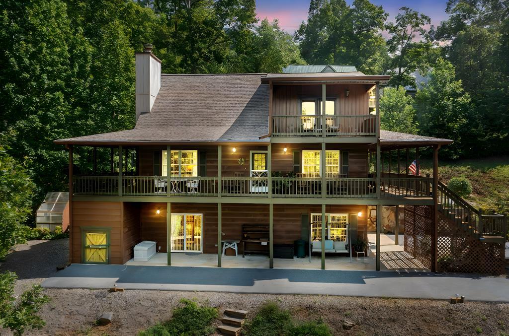 Escape to a charming retreat nestled in the North Georgia Mountains! This classic cabin offers breathtaking views of the majestic peaks and seasonal glimpses of Lake Chatuge, all just minutes from downtown Hiawassee, GA. The exterior features a spacious asphalt driveway with ample parking, a wraparound deck perfect for savoring the scenic surroundings, and beautifully landscaped grounds. Step inside to an open-concept haven with a warm wood interior and tile floors. The stunning great room captivates with a stacked stone gas fireplace and soaring cathedral ceilings, blending comfort and elegance. The gourmet kitchen is a chef's dream, boasting stainless-steel appliances including a gas stove, granite countertops, a farmhouse copper sink, unique custom cabinetry, and a convenient wet bar. Enjoy meals in the adjacent dining area, seamlessly connected to the main level's inviting guest bedroom and a well-appointed bathroom. Upstairs, a spacious loft sitting area offers an office area and a second tv room, plus a luxurious master suite with vaulted ceilings and a private balcony for serene mornings. The lower level provides a versatile third bedroom, an additional bathroom, an oversized one-car garage, and a practical workshop space. This mountain gem is the perfect blend of rustic charm and modern luxury-your timeless retreat awaits!