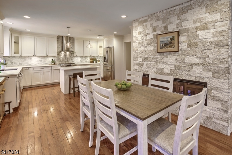 Perched on a scenic hill in the historic Ralston section of Mendham Township, The Treehouse at Roxiticus is a beautifully expanded four-bedroom ranch that surprises at every turn with its generous space, sun-drenched living areas, and modern updates. Gleaming hardwood floors run throughout the home, adding warmth and elegance. Thoughtfully designed for the ease of one-floor living, the home also features a separate ground-level entrance offering flexibility and convenience.The updated kitchen is a standout, featuring quality white cabinetry, designer countertops with matching backsplash, and sleek stainless-steel appliances. This inviting space flows seamlessly into a comfortable sitting area with a TV and gas fireplace, an open living room and dining room creating an ideal setting for everyday living and entertaining. Sliding doors lead to a full wraparound deck, where you can relax and take in the peaceful views from either the front or the back of the home, truly capturing the elevated "treehouse" feel. The main level includes three spacious bedrooms and two full bathrooms. The lower level offers additional versatility with an additional bedroom and a den/office/exercise room, a full bath, and direct access to the garage. Located in a community known for its top-ranked schools and charming downtown, the property also offers a convenient commute to Morristown or Peapack for direct NYC train service.