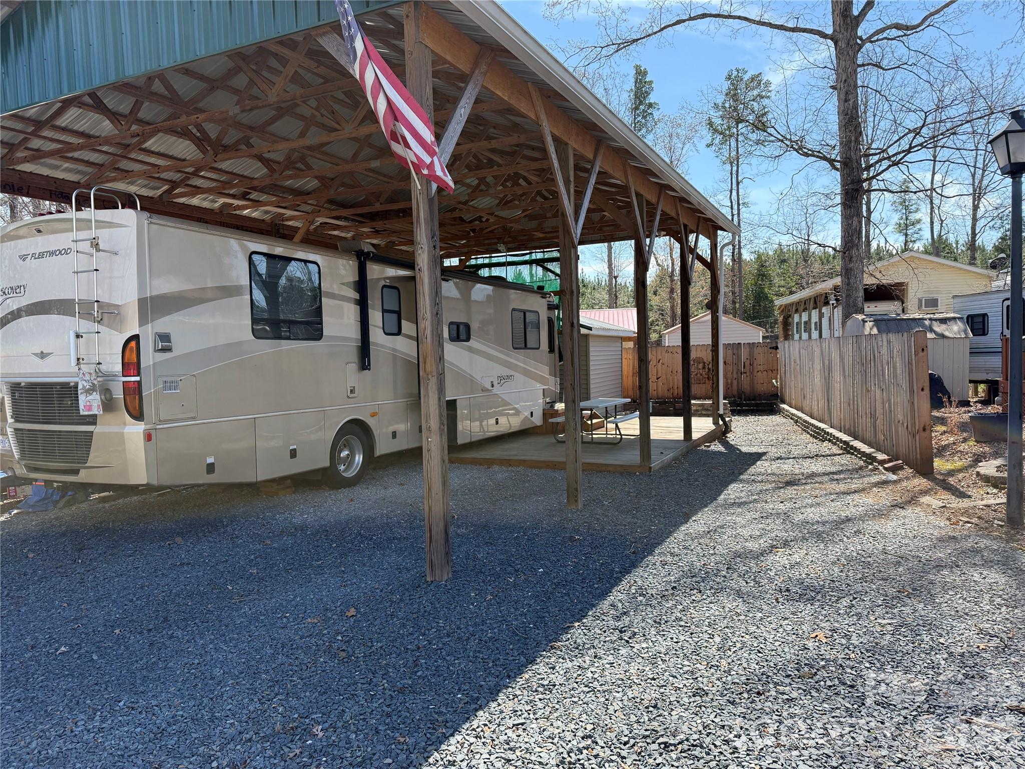 Here is an opportunity to hit the road and enjoy America with the well maintained 2006 Discovery by Fleetwood Motorhome. Caterpiller diesel motor. 39' with 3 slides. 2 super slides in the living area provides plenty of space and an additional slide in the bedroom. 2 couches in living room and both convert to beds as does the dining room table. Plenty of sleeping. Comfortable queen size bed with memory foam. Washer/dryer unit in closet of bedroom. Dual A/C's for plenty of cool in the summer. Propane and elce heat to handle the winters. 6 ft Privacy fence with gate that will accommodate a car, golf cart and jet skis behind lock and key. Enough space to park one car under cover. 12 x 11 fully insulated storage building with electric and shelving. Retaining wall is tied the posts of the pole barn for additional support. Updated power 50 amp for main Motor Home and 30 amp for your weekend guest. Nice covered deck for outdoor space. Stone fire pit out back for the cold winter nights. Stairs to RV roll away with ease. An additional electrical outlet is ready for an addition RV to stay for a weekend. Good size built in generator as well. Come and see if this could be your "Happy Place" here in the park and across America. All clients must be with an agent to gain access to the community. Motor Home can be sold separately for $55k. Lot cannot be sold separately unless Motor Home has been sold.