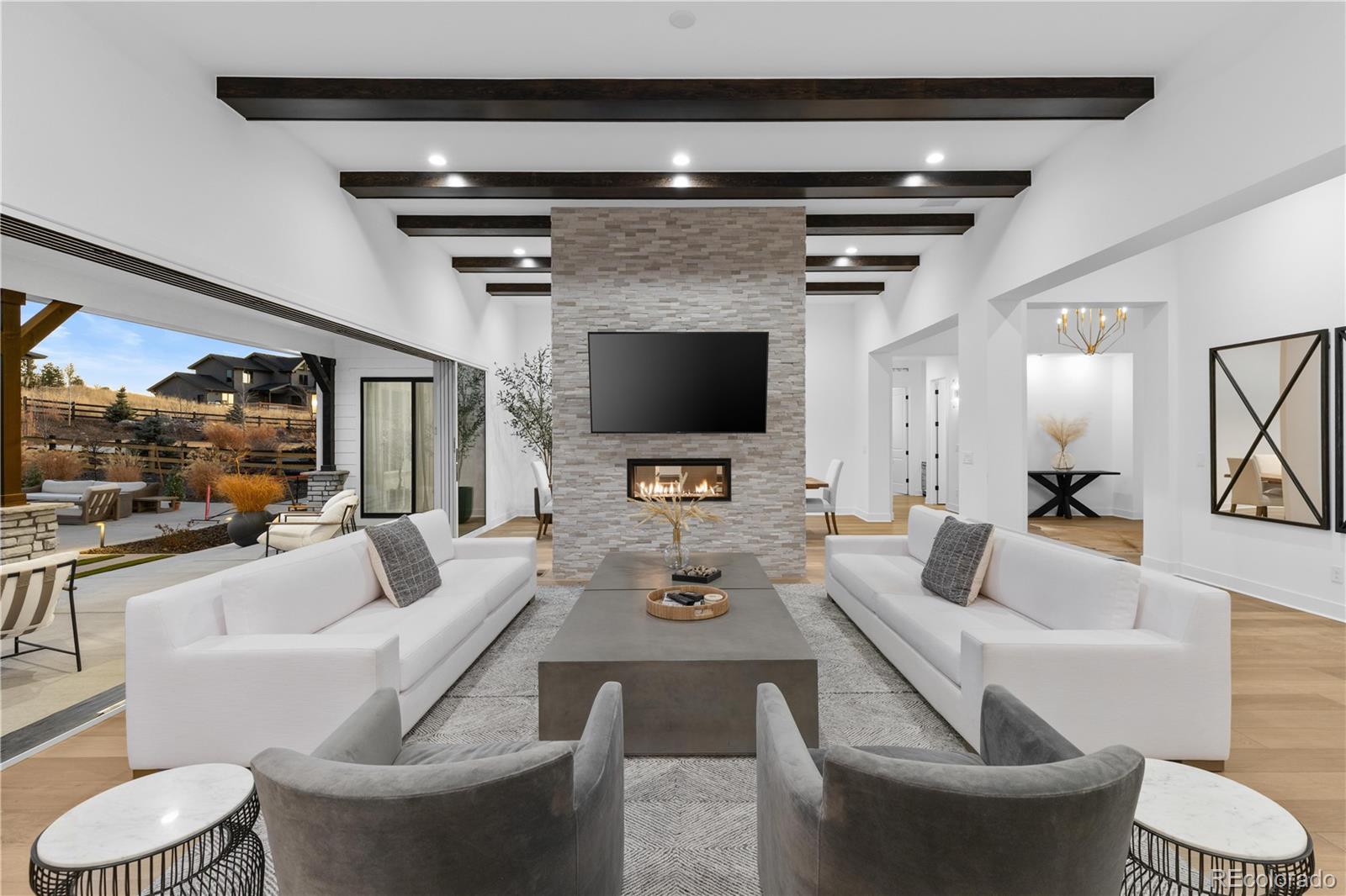 Welcome to the coveted Timbers at The Pinery situated on over a fully fenced half-acre, the professionally designed grounds showcase more than 35 mature and newly planted trees, premium-grade turf, and over 3,300 square feet of concrete designed for effortless entertaining. Multiple outdoor living and dining spaces provide room for gatherings of any size — even space to play pickleball. Nearly maintenance-free living means no lawn mower required.Inside, the meticulously maintained ranch-style residence offers an open, light-filled floor plan accented by extensive 8 ft plank luxury hardwood flooring and custom designer lighting throughout. The great room is anchored by a dramatic 24-foot multi-panel sliding glass door, creating a seamless indoor–outdoor Colorado experience. Vaulted ceilings with exposed beams, a formal dining area, and a striking double-sided floor-to-ceiling stacked stone fireplace add warmth and architectural presence.The gourmet kitchen is a true showpiece, appointed with luxury JennAir appliances including a 6-burner gas range with separate griddle and 4 ovens. Custom floor-to-ceiling cabinetry, a waterfall quartz island, and a full-slab quartz backsplash complete the sophisticated design.The spacious primary suite offers private patio access, a tray coffered ceiling, and serene backyard views. The spa-inspired bath features a freestanding soaking tub, oversized walk-in shower, dual vanities, and a generous walk-in closet.Two additional main-level bedrooms each include private baths and walk-in closets, while a versatile bonus room provides flexibility for a home office or formal living space.The finished basement is an entertainer’s paradise-featuring a dedicated home theatre, a massive wet bar complete with beverage fridge and dishwasher, two additional bedrooms, a full bath, and nearly 1,500 square feet of unfinished space ready for your vision.Colorado luxury living-refined, private, and designed for the way you live.