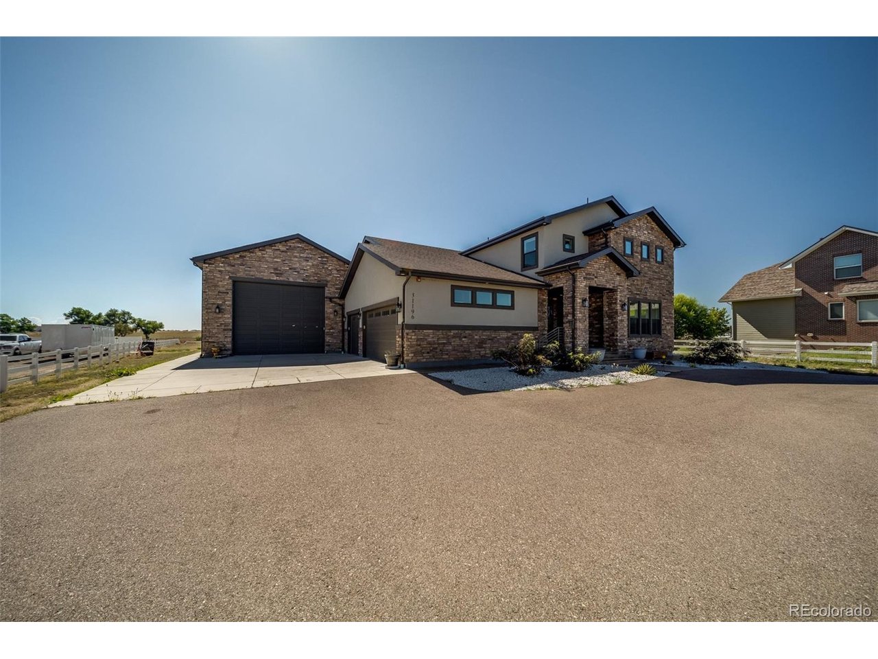 Welcome to an exceptional three-acre estate offering more than 6,100 square feet of luxury living. Built in 2018, this impressive residence features six bedrooms, six bathrooms and garage space for up to 10 vehicles. The dramatic great room showcases soaring ceilings and a floor-to-ceiling stone fireplace, flowing seamlessly into a chef-inspired kitchen equipped with upgraded appliances and two massive 10-foot Cambria islands, perfect for cooking, gathering and entertaining.A spacious main-level suite offers a sitting area, five-piece bathroom, custom walk-in closet and private laundry room, creating an excellent option for multigenerational living. The finished basement expands the home's entertainment possibilities with a wet bar, theater area and plenty of space to relax or host guests. With generous living spaces, upscale finishes and room for vehicles, hobbies and recreation, this remarkable Brighton property delivers luxury, privacy and functionality-all within convenient reach of the Denver metro area.