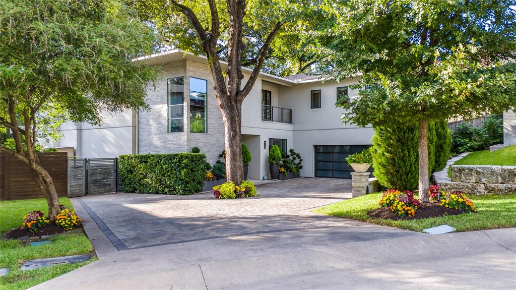 An extraordinary sanctuary in the heart of Dallas, this creekside estate in the gated enclave of Kessler Reserve is a rare blend of modern architecture, natural beauty, and effortless luxury. Situated on the largest lot in the community, this stunning modern transitional home lives like a sophisticated treehouse, with panoramic walls of glass that invite the surrounding landscape beautifully indoors. A breathtaking approach sets the tone, with a delightfully landscaped drive, elegant paver motor court centered around a majestic Elm, sleek glass garage door, & dramatic landscape lighting. Inside, the light-filled open-concept design made for both elevated entertaining and everyday ease. The eat-in chef’s kitchen is a true showpiece, anchored by an oversized earthen-stone island, Viking appliances, and custom rift-cut white oak cabinetry. The adjacent dining & living spaces unfold seamlessly, all oriented toward sweeping views of the private backyard retreat and wooded creek beyond. With soaring 11-foot ceilings, a striking stone-surround gas fireplace, and a modern take on the Sputnik chandelier, the living room is warm, refined, and unforgettable. A wraparound deck extends the living experience outdoors, perfect for sunset cocktails, candlelit dinners, and evenings under the stars. A gracious first-floor guest suite completes the main level. Upstairs, the primary suite is a true sanctuary, offering a spa-inspired bath with dual vanities, Ann Sacks limestone, a 6' aerated soaking tub, and a walk-through shower. A custom closet and dual water closets complete the suite. Two additional ensuite guest rooms and a versatile flex space for living or office round out the upper level. Beyond, the grounds are nothing short of magical—beautifully designed to evoke peace, privacy, and tranquility, with birdsong, a bubbling fountain, illuminated pathways, layered hardscapes, and lush, artful plantings. A true retreat. A true experience. A home that lingers long after you leave.