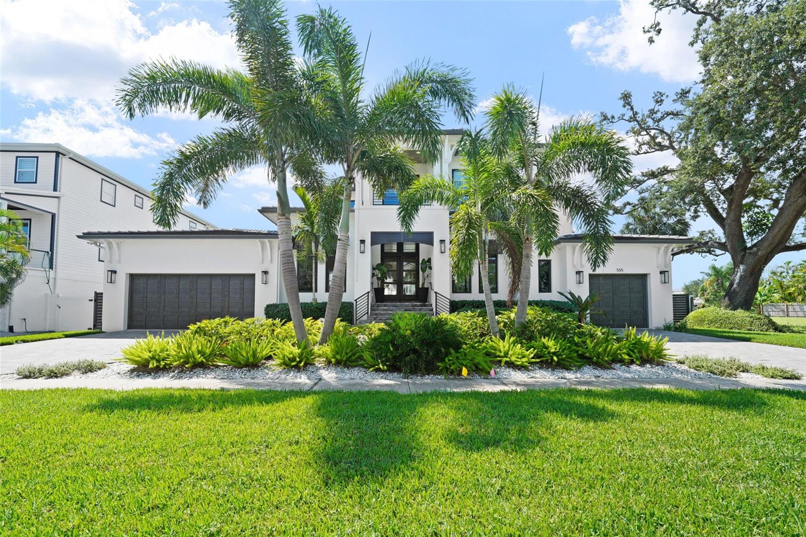 Davis Islands Modern Coastal on 100’+ of Waterfront with first-floor master bedroom. This custom-built residence blends timeless design with the highest standards of craftsmanship and is located on a quiet street on Davis Islands. 
The entry showcases a custom contemporary mahogany six-panel front door with impact glass and transom, opening to light-filled interiors defined by white oak engineered hardwood floors. A glass-fronted refrigerated wine cellar—with split-system cooling, floor-to-ceiling wood tile, stainless steel wine racks, a mahogany solid wood door, marble floors, custom cabinetry, and an electronic lock—serves as both functional storage and a striking design feature. The chef’s kitchen pairs marble counters and backsplash with premium appliances, complemented by a butler’s pantry and walk-in pantry. Living areas flow seamlessly to the outdoors through a 4-panel impact pocket slider, while PGT high-impact bronze windows with transoms on the front and rear elevations frame every view. Every element of the home reflects thoughtful engineering and luxury detail—from its piling foundation and concrete flat tile roof to the light sand finish stucco and custom Bahamian shutters with crafted metal railings and fencing that frame the façade. The primary suite offers two walk-in closets and a spa bath finished with imported marble flooring, counters, and shower, plus a freestanding soaking tub. Additional bedrooms include en-suite baths with marble finishes, continuing the home’s refined material palette.. At the water’s edge, a new seawall supports a composite dock with a covered 13,500lb boat lift—finished with a metal roof, lighting, water, and electric service. An additional electric 1,500lb lift lowers directly into the water, easing access for boating or water toys. The backyard is a showcase for Florida living: a contemporary rectangular saltwater pool with water-edge spa, glass waterline tile, umbrella stand, lounge area, and automated Hayward LED lighting. Surrounding the pool and lanai, silver travertine pavers set the stage for gatherings. The lanai’s cypress coffered ceiling frames a linear gas fireplace with a tabby shell stucco surround and a custom barnwood mantel, while a custom outdoor kitchen—featuring a Blaze grill and smoker with a double hood, stainless steel backsplash, beverage center, concrete counters, sink, and an Ipe wood surround—makes entertaining effortless. A plumbed outdoor shower with hot and cold water completes the resort feel. Six gas lanterns accent the entry and garages, bringing coastal character to evening hours. The oversized three-car garage offers versatility with a deep two-car bay (workbench and storage included) and an extended one-car garage sized for a golf cart. A whole-house generator ensures comfort and security year-round. Come enjoy the DI lifestyle with its walking and bike path, and just a short distance away from Davis Islands Village with many restaurants, shops, and bars. Bring your golf cart and enjoy the Island lifestyle with baseball fields, public tennis courts, a public historic pool, two dog parks (one wet and one dry), a beach, a public marina, and an airport. Located only minutes from Downtown Tampa, Water Street, Sparkman Wharf, and the Tampa Riverwalk, this neighborhood is the most desired in South Tampa!