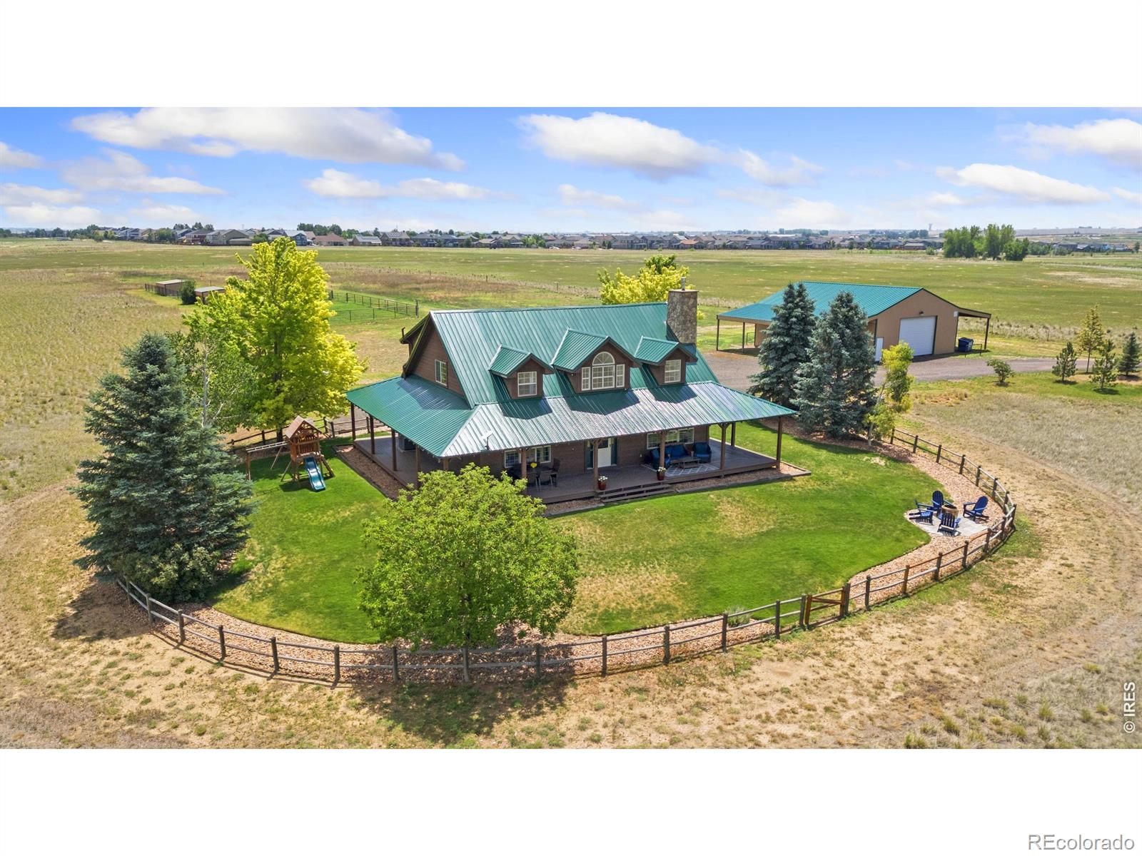 Discover the freedom of Colorado acreage living without sacrificing convenience at this exceptional top of the hill 18-acre estate. Ideally located just minutes from I-25, premier shopping, dining, and everyday amenities. Beyond the semi-private drive you'll discover a beautifully maintained home that embraces the warmth and character of Colorado country living. The expansive wraparound porch provides the perfect setting to enjoy spectacular sunrises, mountain sunsets, and peaceful views in every season. Enjoy the unobstructed mountain views spanning the entire Front Range from Wyoming to Colorado Springs. Interior space includes soaring ceilings, expansive windows, warm wood finishes, and a dramatic stone fireplace contributing to an inviting atmosphere filled with natural light. Spacious living areas blend rustic charm with everyday comfort, making the home ideal for both relaxing and entertaining. Designed for equestrian and outdoor enthusiasts, the property features fenced paddocks, horse facilities, detached outbuildings, a large shop with 220-volt power, covered RV storage, and ample space for equipment, trailers, recreational vehicles, or future improvements. Whether your vision includes horses, hobby farming, additional barns, or simply room to enjoy Colorado's open spaces, this versatile property offers endless possibilities.Lovingly maintained and move-in ready, the home also presents an exciting opportunity to personalize the existing residence or explore the potential to build an additional home on the property (subject to county approval), creating a legacy estate tailored to your vision.Relax around the outdoor fire pit, entertain beneath Colorado's endless skies, and enjoy the peace, privacy, and beauty that only acreage living can provide. Underground utilities preserve the spectacular views, while mature landscaping enhances the property's serene setting.