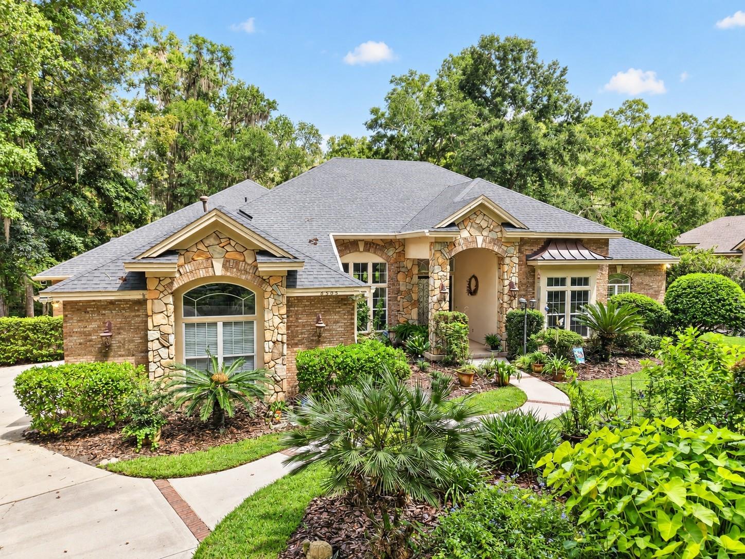 Virtually Staged. Set on a private 2-acre homesite within the gated community of San Felasco Estates, this custom-built Tommy Waters residence offers an exceptional combination of timeless architecture, gracious living spaces and resort-style outdoor living in one of NW Gainesville’s most desirable settings. Set well back from the road and surrounded by spacious landscaping, the home enjoys a wonderful sense of privacy from the moment you arrive. The property backs to natural marshland and a beautiful wooded backdrop, offering peaceful views and opportunities to enjoy the area’s native wildlife.From the moment you enter the foyer, soaring 12-foot ceilings, rich wood flooring and thoughtfully designed architectural details create a sense of scale and sophistication. The open, flowing floor plan is equally suited for elegant entertaining and comfortable everyday living, with formal living and dining spaces leading into an impressive chef’s kitchen. Designed for those who love to cook and entertain, the kitchen features granite countertops, abundant custom cabinetry and professional-grade stainless steel appliances, including a Wolf gas range and Sub-Zero refrigerator.At the heart of the home, the dramatic family room features a gas fireplace, custom built-ins and architectural niches, while French doors provide beautiful views and effortless access to the pool and outdoor living areas. An expansive adjoining game/media room with vaulted ceilings provides incredible flexibility as an entertainment space, additional gathering room or optional 5th bedroom.Privately positioned, the spacious primary suite offers a peaceful retreat with a tray ceiling, sitting area, generous walk-in closet and spa-inspired bath. An adjoining private study is ideal for a home office, library or quiet sitting room. Three additional guest bedrooms and two full baths provide comfortable accommodations for family and guests.Outdoor living takes center stage with a screened pool overlooking the expansive backyard and natural surroundings beyond. A wrought-iron-style fence defines the backyard while preserving the views and open feel of the property. Adding to the home’s appeal is an extensive solar system featuring 34 American Solar panels designed to generate electricity and help offset utility costs, along with 8 additional solar panels dedicated to pool heating. The circular driveway with two entrances provides convenient access, generous parking and an inviting approach to the home.Beyond the property itself, San Felasco Estates offers a scenic neighborhood setting with winding roads and multiple green spaces that provide an inviting backdrop for morning or evening walks. Located just off scenic Millhopper Road, the community offers the privacy and space of estate living while remaining convenient to Gainesville’s shopping, dining, medical facilities and the University of Florida. With custom construction, expansive living and entertaining spaces, a private pool, energy-conscious solar features and a beautiful 2-acre setting, this exceptional home offers a rare combination of privacy, space, natural beauty and convenience in NW Gainesville.
