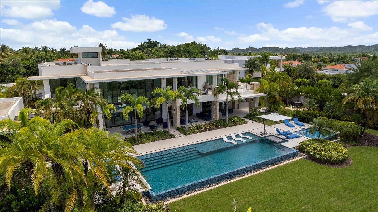 Discover an extraordinary estate in the Legacy neighborhood of Dorado Beach Resort and Club, where luxury, privacy, and exclusivity converge. Set on an expansive 4,800-square-meter property, this home offers an unparalleled amount of land within the resort, making it one of the most unique opportunities on the market. Boasting 16,746 square feet of gross construction, it is situated on one of the most secluded streets, offering a rare sense of peace and tranquility.What truly sets this estate apart are its rare and custom amenities. A two-lane bowling alley offers a unique entertainment experience that is virtually unheard of in a private property. Alongside this, a private half-basketball court and multiple entertaining spaces make the home ideal for hosting both intimate gatherings and grand events. Outdoors, a covered BBQ kitchen, complete with a custom spit, and a poolside dining table bring alfresco dining to life under the stars.Inside, the estate unfolds with grandeur, featuring a thoughtful layout designed for both comfort and luxury. On the main floor, you'll find three beautifully appointed bedrooms, each with expansive windows that invite natural light and provide private terraces. Upstairs, two additional bedrooms are complemented by the lavish primary suite, which spans an entire side of the second floor. The primary suite offers ultimate luxury with an oversized private terrace, a spacious walk-in closet with an island, and a spa-inspired bathroom, complete with an outdoor shower for a resort-like experience. Across from the primary bedroom is a private office, providing a serene space for work or relaxation.In addition to the main living areas, a separate guest suite with its own entrance and serene garden provides privacy and comfort for visitors. For further indulgence, the estate features a dedicated space for a private hair salon, enhancing the home’s one-of-a-kind appeal.The design elements throughout the property reflect impeccable attention to detail, from the double-height ceilings in the living room to the custom hand-blown chandelier that adds an artistic touch. With its fully integrated audio-visual system, Crestron home automation, and stunning architectural elements, this estate is a masterpiece of modern luxury living.This exclusive property offers a lifestyle of unmatched sophistication, combining bespoke design, custom amenities, and an extraordinary amount of space within one of the island’s most sought-after resorts, Dorado Beach Resort and Club.