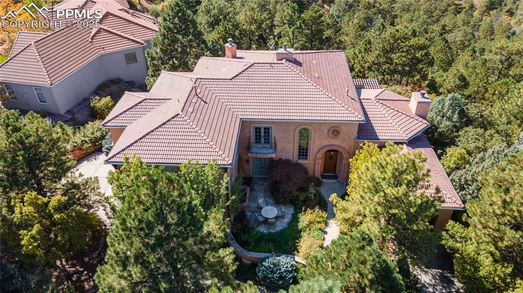 Welcome to 4896 Stonehill, where Old World artisanship meets modern luxury. This extraordinary residence showcases antique architectural treasures and custom features throughout.A hand-carved stone door surround frames the oversized entrance, complemented by gas copper lighting and a stone wall fountain. The flagstone patio and walled garden create a private sanctuary.Soaring 10-21 foot ceilings grace the first floor, with 9-foot ceilings upstairs. Travertine flooring with radiant heating, oversized 8-foot doors, and authentic Venetian plaster installed by artisans from Venice, define the interior. The foyer features hand-carved railing and ironwork from France with custom Tibetan carpeting. The living room showcases a hand-carved limestone fireplace and antique Chinese Compound doors concealing a wet bar, The family room offers hand-hewn wood ceilings.The chef's kitchen includes custom inset cabinets, marble-topped table, and granite countertops with Pikes Peak views. The outdoor patio features a built-in cooking center with gas grill and stone countertops.The service area includes a dog room with plumbing connected to an outdoor run, coat closet, and gift wrapping center.Upstairs, the primary suite opens to a balcony with waterfall and Pikes Peak views. The spa bathroom includes radiant heat and hidden TV. The custom maple closet features 46 drawers with in-closet laundry, connecting to a workout room.Two guest suites offer Juliet balconies and ensuite baths. One features a vanity from antique French railing with freestanding tub.The theater room provides tiered seating and projection system behind an antique Moroccan door. An additional bonus/craft room is located upstairs. It can easily be converted to an additional bedroom. The wine cellar houses racking for over 500 bottles.The lot is amazing. It is private and backs to open space with direct views of Pikes Peak.
4896 Stonehill Road represents unprecedented craftsmanship—not just a home, but a work of art.