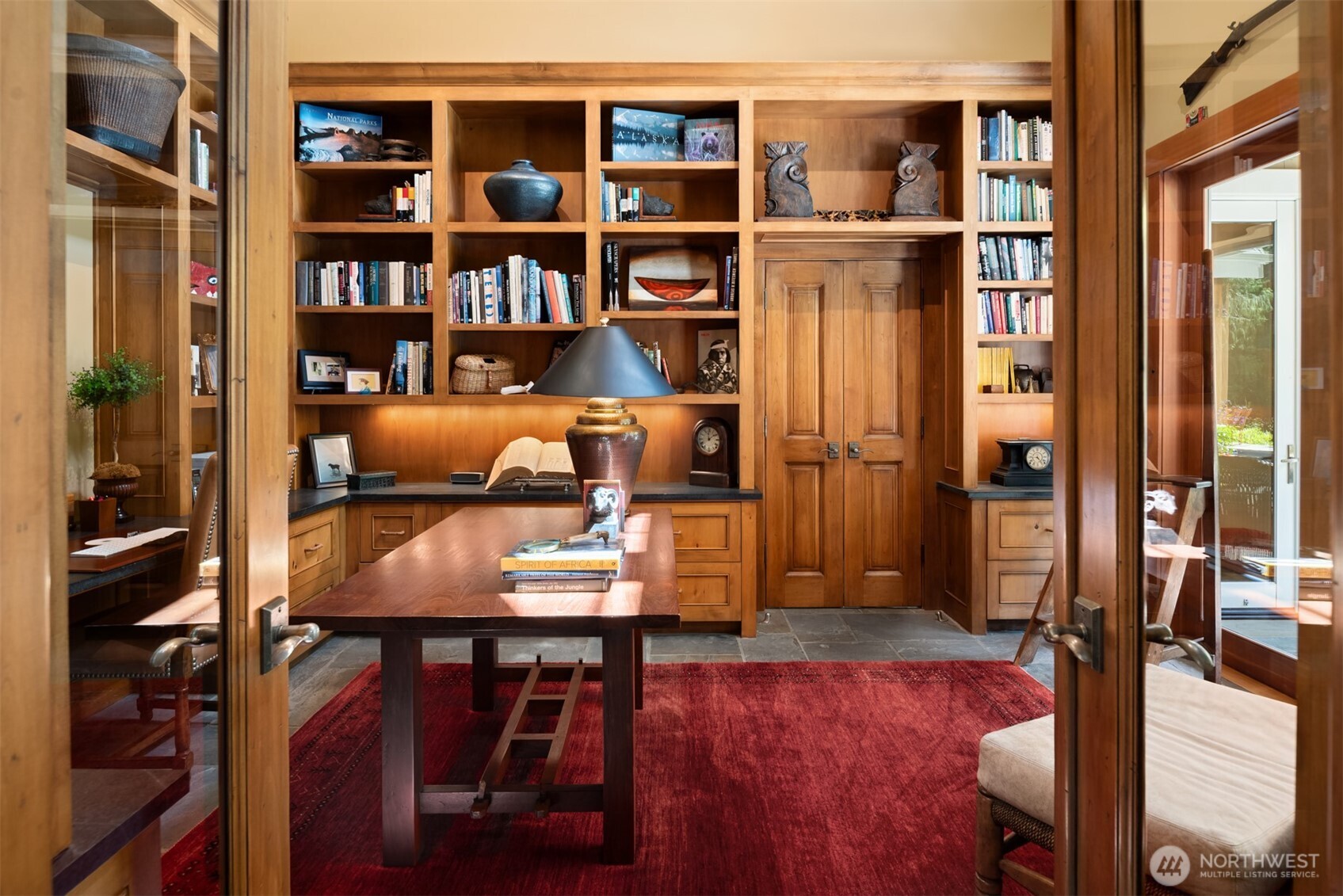 Home office with built-in bookshelves and red area rug