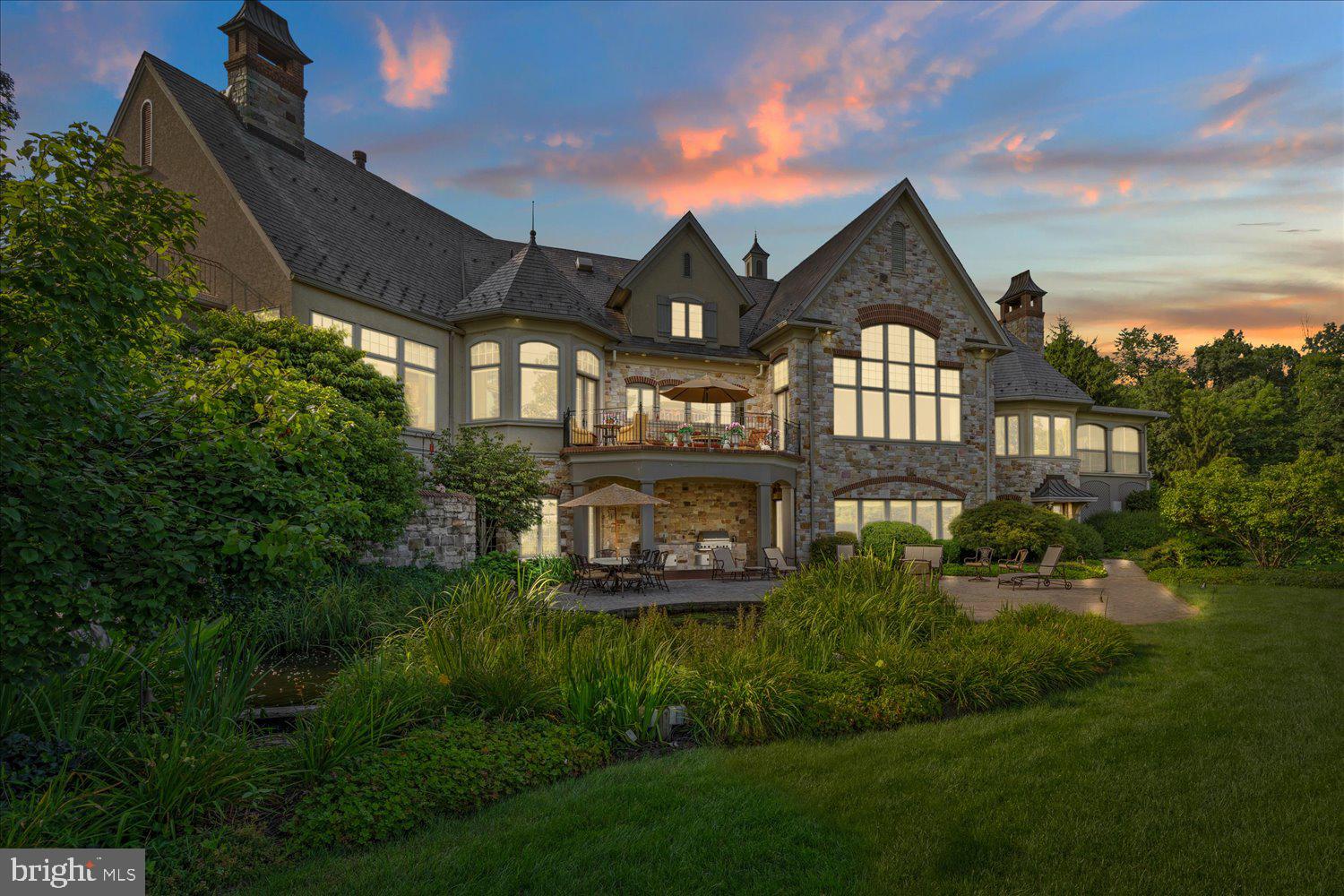 Nestled on a gorgeously manicured lot amid 10 secluded hilltop acres, this five-bedroom, 12,000+ sq-ft architectural masterpiece was lovingly designed by acclaimed architect Don Klinger to provide its owners supreme comfort and functionality while offering breathtaking views of the Susquehanna River Valley from nearly every room. With amenities too many to list (a sampling would include the five ensuite full baths plus four additional half-baths, the six fireplaces, and the 16,000-gallon outdoor koi pond with cascading waterfall), Hawkridge Estate takes mountain-side luxury living to a new level.Situated at the end of a private, wooded drive within a gated community, the mansion features an all-natural stone façade and grey slate roof, with a spacious circular driveway and a broad double garage cleverly hidden to the side. The lofty entrance portico guides visitors into a stately hand-chiseled limestone foyer adorned with shimmering chandeliers and a sweeping, wooden grand staircase that curls upward to the second-floor bedrooms and a luxurious executive office suite.Warm, sophisticated opulence characterizes every room of this three-story home, from the Great Room’s massive 24’-high beams and 1800-lb, no-seam rug imported from Thailand, to the elaborately hand carved millwork of the formal dining room. The expansive chef-quality kitchen features 200-year-old white oak floors, two-tiered solid granite counters, more than ample cabinet space, and a walk-in pantry. The regal owner’s retreat includes oversized closets and a jacuzzi surrounded by stained-glass windows. Hand-painted decorative tray ceilings throughout the house highlight natural motifs of plants, florals, and wildlife, elegantly complementing the house’s soothing earth-tone palette and Country French interior theme. The result is a retreat that is both luxuriously comfortable and hospitality ready.