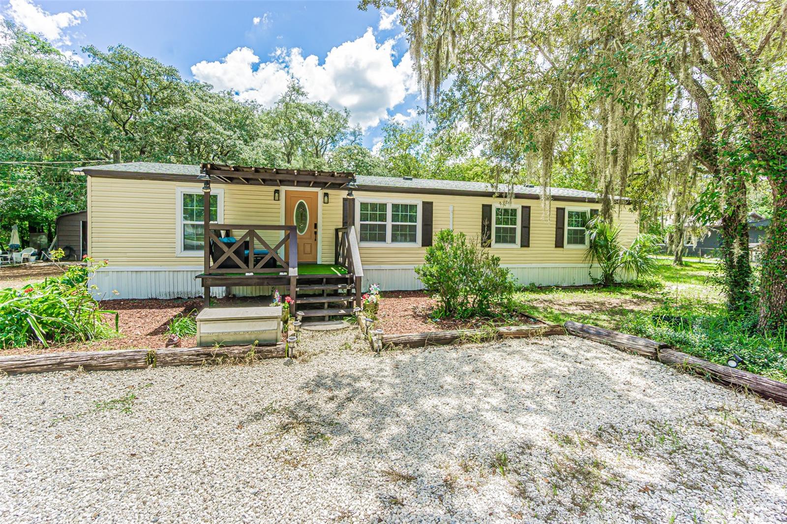 Welcome to this beautifully remodeled 5-bedroom, 3-bath manufactured home situated on 1.09 acres, offering an exceptional combination of space, privacy, flexibility, and outdoor living. Located on a paved road outside of a flood zone, this property has no HOA and no CDD fees, with plenty of room for vehicles, recreational equipment, hobbies, animals, and more.The home has been extensively updated inside and out and features a desirable split-floor plan with a private 1-bedroom, 1-bath in-law suite—ideal for multigenerational living, guests, or added privacy. The in-law suite bathroom also conveniently functions as a pool bath, providing easy access from the outdoor living and pool area. Interior updates include new flooring, remodeled bathrooms, a beautifully updated kitchen with granite countertops, and fresh interior paint. Major improvements include a roof installed in 2024, a water heater installed in 2024, and an A/C system from 2018. Outside, the home has been freshly painted and features updated windows, mature landscaping, improved front and rear porches, and white gravel that provides additional parking space. The property is served by a private well and a septic system.Outdoor living is one of the highlights of this property. Relax on the screened-in back porch overlooking the above-ground pool and surrounding deck, creating a private space for entertaining, grilling, or simply enjoying the Florida lifestyle. The mostly fenced property also includes a separate fenced grassy area and chicken coops, offering additional possibilities for pets, gardening, chickens, and other outdoor uses.For those needing serious garage, storage, or workspace, the freshly painted, 720-square-foot detached garage is a standout feature. With room for oversized vehicles, it can easily accommodate a workshop, hobby space, additional storage, or the ultimate man cave. The expansive property also provides abundant parking for multiple vehicles, trailers, boats, RVs, or work equipment.Come experience the space, privacy, and possibilities this property has to offer. Schedule your private showing today!