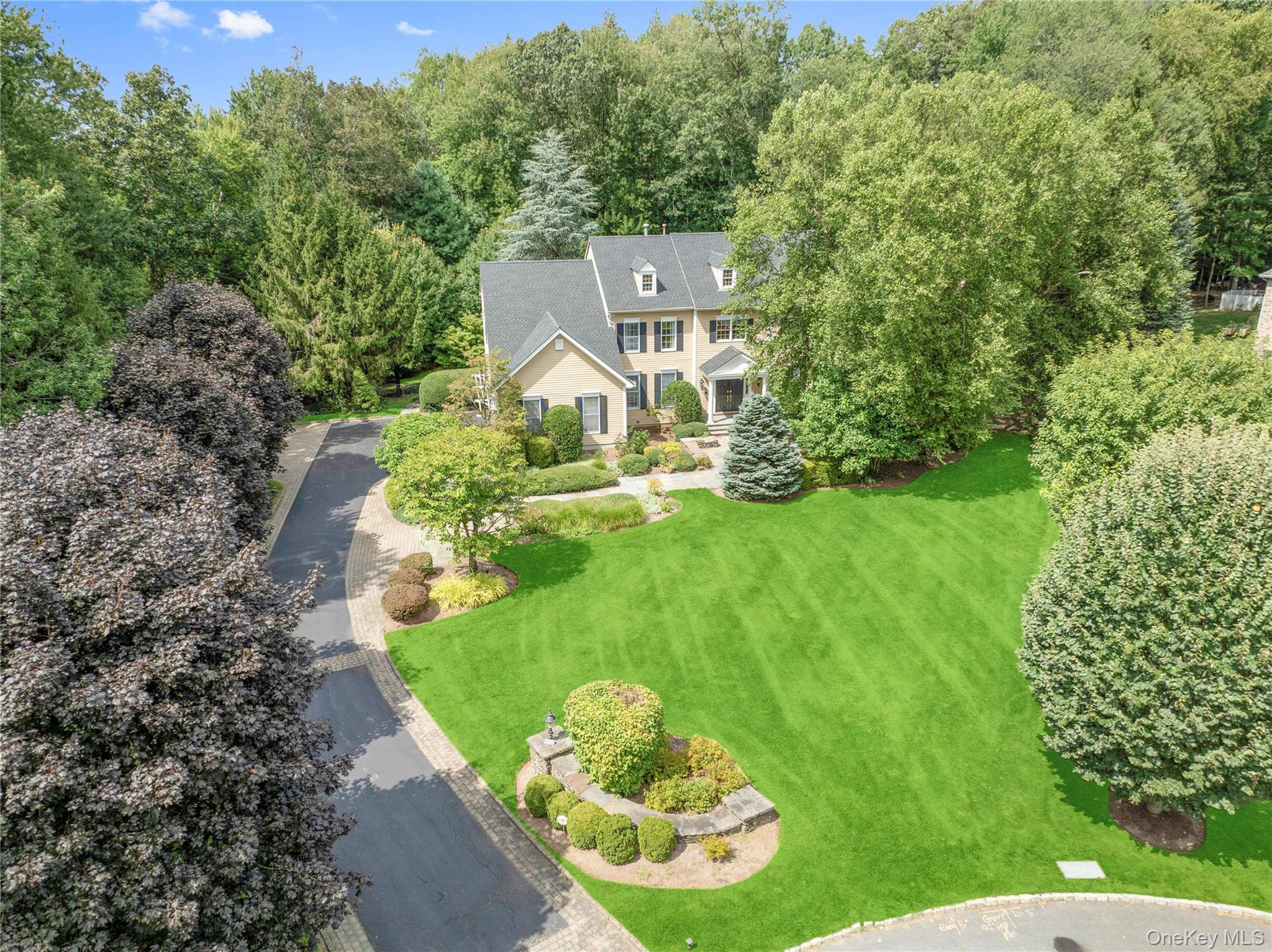 Welcome to this timeless center-hall Colonial set on beautifully landscaped grounds in the sought after Leisure Farm community. A long private driveway with brick-pillared entry and graceful curved wall leads you to this 4-bedroom, 4.1-bath classic elegant home with thoughtful design throughout.
The impressive two-story foyer with coffered ceilings opens to formal dining room with tray ceiling and living room with adjoining library/sitting room featuring a builtins with marble gas fireplace. The expansive family room with wood-burning stone fireplace seamlessly connects to the breakfast room and chef’s kitchen, complete with sit-down island, convenient desk area, and butler’s pantry. Sliding glass doors lead to multi-level decks, bluestone patios, built-in gas barbeque and a private backyard oasis with heated freeform Gunite pool, spa and waterfall.
Upstairs, the primary suite offers two walk-in custom fitted closets, a private office with custom wood built-ins, a primary bath with whirlpool tub, dual vanities, heated floors and separate shower. Two bedrooms share a Jack-and-Jill bath, while an additional ensuite bedroom features a walk-in closet and private bath.
The finished walkout lower level is designed for entertaining with full size, custom wood, wet bar, 500 bottle wine cellar, full bath, and flexible guest/office space; plus plenty of room for work out area, or to watch your favorite movie or a game of billiards. Convenient walk out area to the fenced in backyard. Outdoors, lush gardens and mature trees frame a resort-style heated Gunite pool with spa and waterfall; ideal for gatherings, poolside lounging, or simply relaxing in total privacy. A 3-car garage, hardwood floors & custom molding throughout, full service laundry room, and mudroom complete this exceptional home.