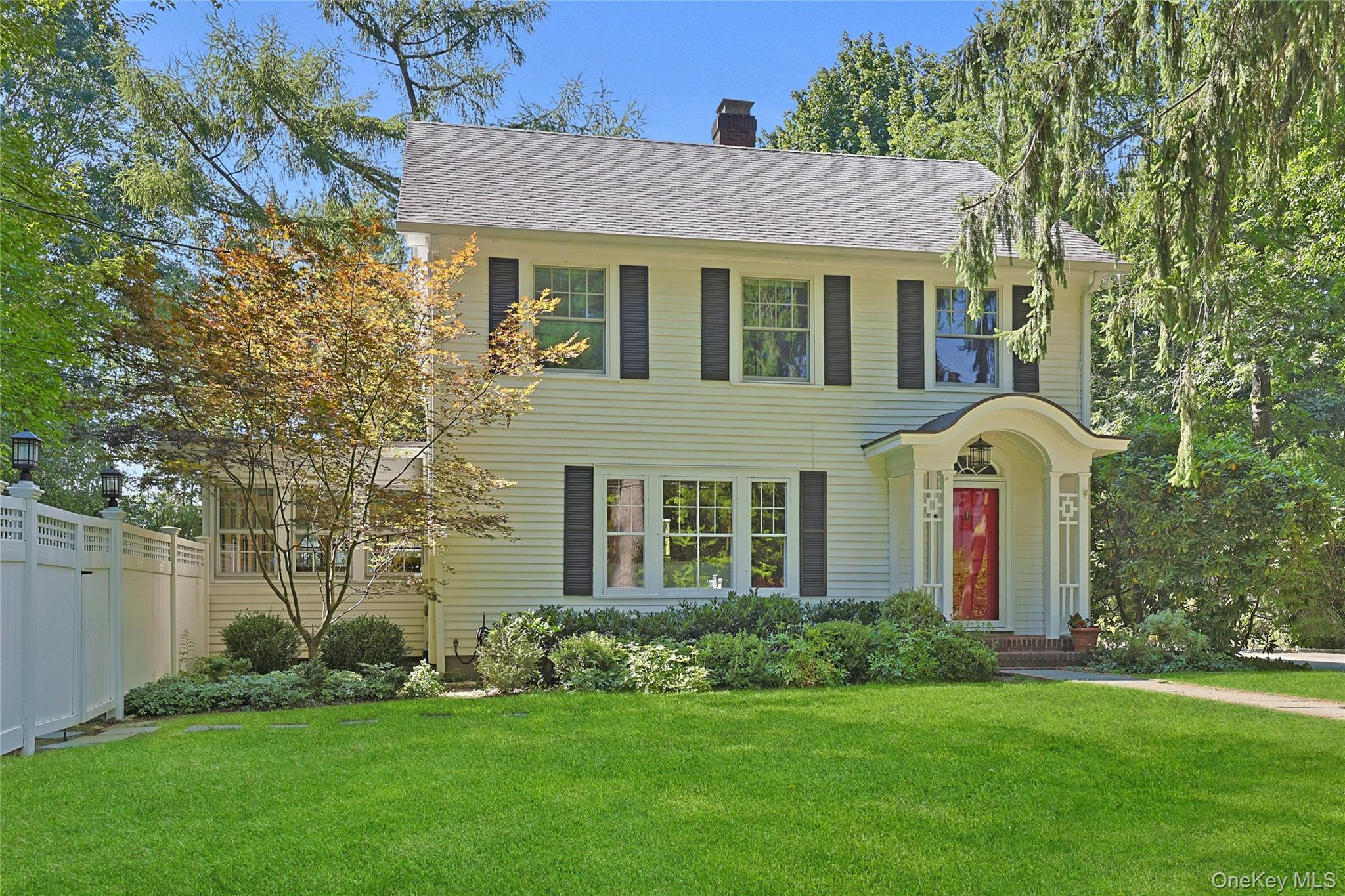 Welcome to 26 Kings Court, Chappaqua, a storybook, village Colonial enchantingly set among towering trees on a quiet cul-de-sac just a short stroll to schools, shops, town and train. If your Brooklyn brownstone could move to the suburbs, this would be it. Regal, barrel-vaulted front portico. Welcoming front entry. French doors introduce the gracious front-facing living room warmed by morning sun and a wood-burning fireplace and accented with built-in cabinetry and hardwood flooring. Adjoining is a traditional formal dining room with chair-rail molding and hardwood flooring. Afternoon sunshine streams into the wonderful white, designer kitchen outfitted with high-end, stainless-steel appliances from Wolf, Sub-Zero and Bosch, and anchored by a large center island with striking butcher block top and breakfast bar. A French door to the deck makes for easy BBQ and alfresco dining. Retreat to the coziness of the sunroom, illuminated by natural light on three sides. Comfort abounds throughout the four, upstairs bedrooms, including the primary with its own sitting/dressing area and private ensuite bath, and in the updated hall bath with marble tile and shower over jetted bathtub. An unfinished, walk-up attic adds more charm and storage. The basement is unfinished and houses laundry, mechanicals and storage. A convenient side entry connects to a flat driveway leading to a detached garage with a separate studio offering flexible space for home office, exercise, or more introspective pursuits. Lush landscaping and lovely yards envelope the residence. A quintessential Chappaqua Colonial.