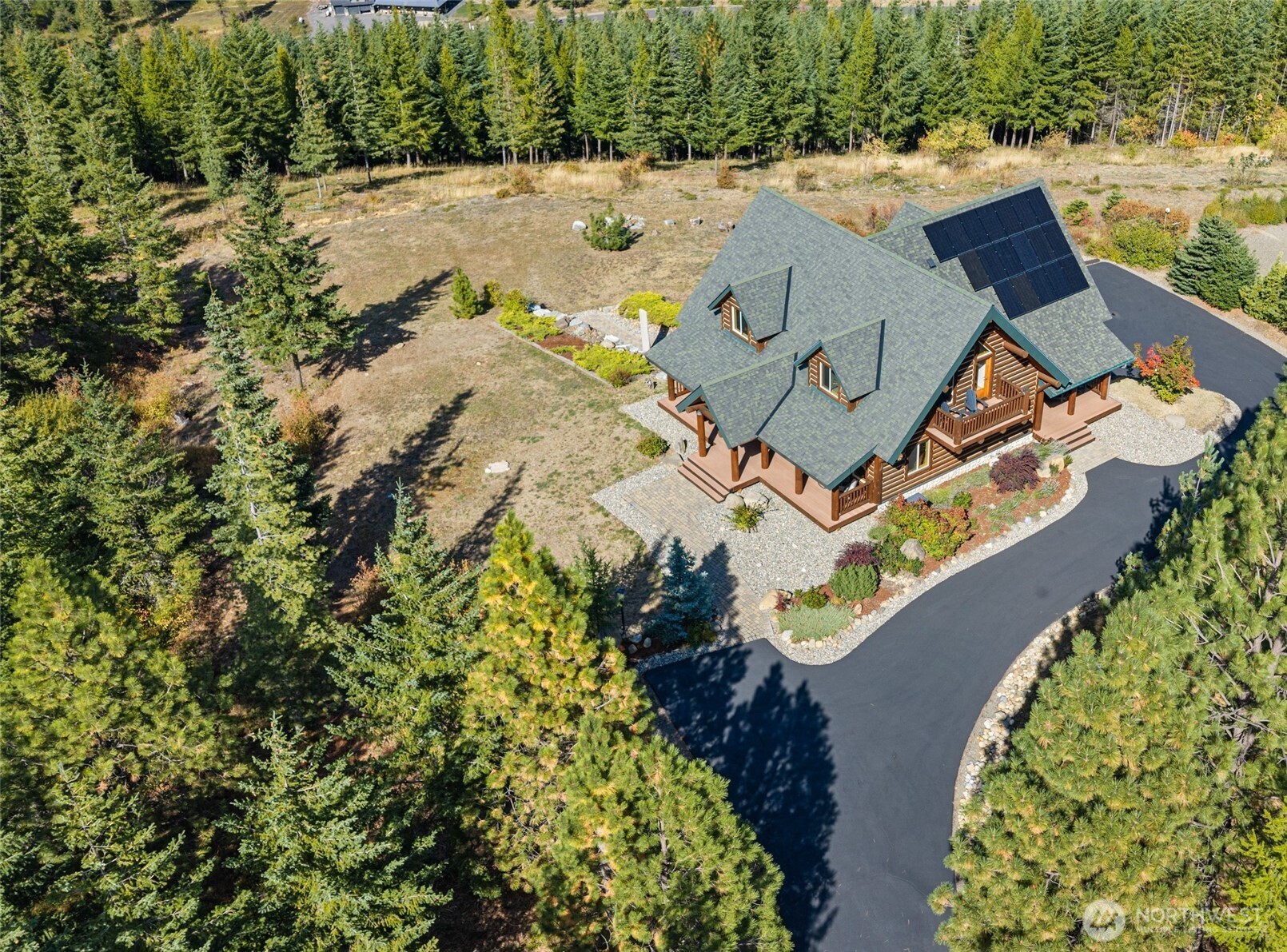 Aerial view highlighting the home’s setting, mature trees, landscaping, and expansive grounds.