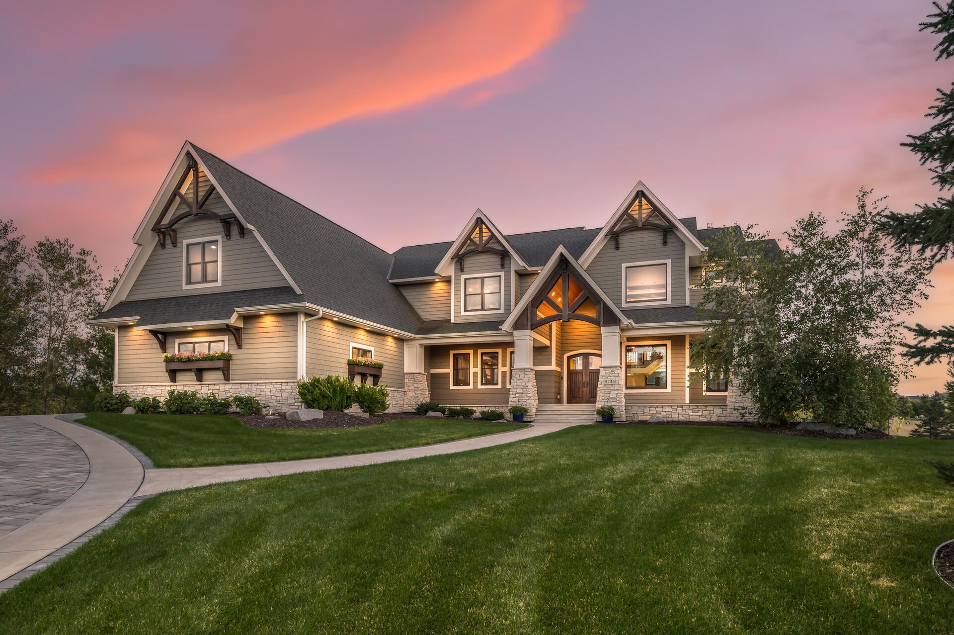 Set high on a hill in a private Lake Elmo neighborhood, this extraordinary custom-built estate offers nearly 10,000 finished square feet with six bedrooms, seven bathrooms, and an elevator serving every level. Designed with uncompromising craftsmanship, the home blends refined luxury with a warm, inviting atmosphere, creating a residence as functional as it is breathtaking.The entry opens through custom double doors into a dramatic two-story great room, where floor-to-ceiling windows frame serene views and a striking stone fireplace anchors the space. Hickory wood floors, rich millwork, and ten-foot ceilings add timeless elegance throughout the main level.At the heart of the home, the chef’s kitchen is both stunning and practical, featuring Alder cabinetry milled on site, granite countertops, double ovens, and Thermador appliances. A ten-foot island with seating encourages connection, while a walk-in pantry and beverage station add convenience. The adjacent dining room flows into a three-season cedar sunroom with fireplace and deck access, ideal for year-round enjoyment.A private mother-in-law suite offers complete independence with its own entrance, garage, full kitchen, laundry, and deck—perfect for guests or residents. Upstairs, the primary suite is a true retreat with an Alder wood tray ceiling, double-sided fireplace, spa-inspired bath, and expansive custom closet. Three additional bedrooms, each thoughtfully designed with private bathrooms, plus a nearby laundry room, complete the upper level.The lower level is an entertainer’s dream with heated floors, a full bar, tiered theater, recreation room with fireplace, 700+ bottle wine cellar, steam shower spa, second laundry room, and walkout access to the pool deck.Outdoors, a resort-worthy pool and pool house offer soaring cedar ceilings, a wood-burning fireplace, grill, powered screens, and built-in speakers. Every detail, from powered window shades to whole-home water purification, reflects thoughtful design and elevated living. This estate is more than a home—it’s a rare opportunity to experience everyday life as extraordinary.