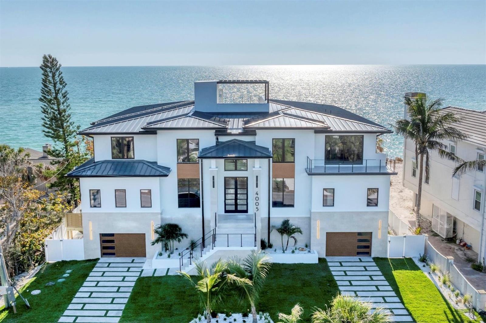 WELCOME TO ONE OF THE FEW BRAND-NEW GULF FRONT HOMES FOR SALE ON THE WEST CENTRAL COAST OF FLORIDA. A rare opportunity, where cutting-edge design meets wide Gulf vistas. Nestled on the prestigious barrier island of Casey Key, this newly constructed Modern Coastal estate by Modesta Homes exemplifies modern beachfront living. Positioned directly on the sand with sweeping Gulf views, this striking residence offers elevated living space, showcasing the pinnacle of craftsmanship and architectural innovation. Built with block construction, pilings, impact-rated windows and doors, and a four-stop elevator, every detail of this home has been thoughtfully curated for style, function, and resilience. Inside, soaring 24-foot ceilings welcome you into the grand foyer and great room, anchored by a dramatic floating staircase and a 24-foot feature fireplace wall. With en-suite bedrooms, state-of-the-art home theater, lounge, bar, and a wine wall, this home offers both grand entertaining and serene retreat. The chef’s kitchen is a design showpiece, featuring European cabinetry, dual waterfall-edge islands clad in book-matched 3cm quartz, and premium Sub-Zero & Wolf appliances. Dual laundry rooms, breakfast nook, and custom built-in vanities provide elevated everyday living.  The primary suite is a personal sanctuary, complete with a spa-like bathroom featuring a 71-inch freestanding tub, dual rainfall showers, a makeup vanity, and a large walk-in closet. Every bathroom throughout the home is appointed with bespoke cabinetry, quartz surfaces, and backlit mirrors. Designed to impress from every angle, the home is finished with smooth stucco, level 5 drywall, hardwood floors, imported tile, and integrated LED tray ceilings. A sleek rooftop terrace crowns the home, offering panoramic views of the Gulf and beyond.  Step outside to your personal resort: an expansive terrace with an oceanfront pool, floating spa, sun decks, outdoor fireplace, and fully equipped kitchen. Lush, tropical landscaping, Zoysia grass, and a concrete drive with turf inlays complete the impeccable exterior design. Sleek metal railings accentuate balconies and the rooftop for a modern edge. Set on a half-acre of prime waterfront. This is coastal modern luxury at its pinnacle—a rare opportunity to own a brand-new, Gulf-front estate on one of Sarasota’s most desirable stretches of sand.