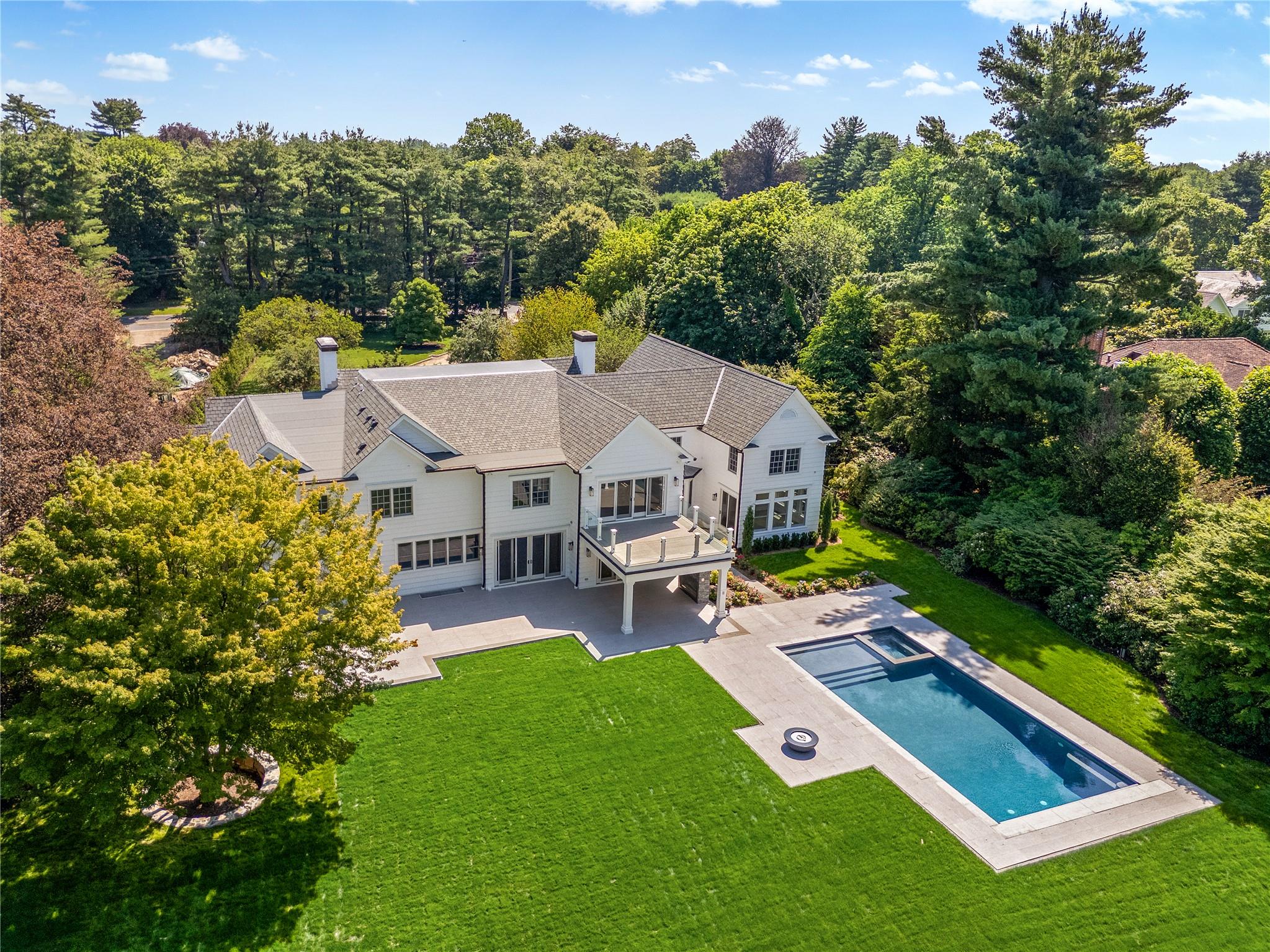 Welcome to 42 Mamaroneck Road, a magnificent iconic estate ideally located in the heart of Scarsdale’s prestigious Murray Hill neighborhood. This impressive property is accessed by a long and supremely private circular driveway enhanced with mature and pristine specimen trees delivering a dramatic sense of arrival. Nestled on 1.5 acres of lush, level, and perfect property, this magical residence has been completely recreated in 2025 and seamlessly blends timeless curb appeal with modern interiors designed for today’s most sophisticated and discerning buyers.

A luminous two-story entrance hall with herringbone floors and a wide sculptural staircase with sleek glass railing sets an inviting and airy tone. The center hall layout offers a well-proportioned living room with a marble fireplace for elegant gatherings. A spacious formal dining room with a custom-crafted butler's pantry and wet bar adjoins the luxurious eat-in kitchen. The expansive open-concept kitchen features a large center island with waterfall quartzite countertop, Thermador appliances, including 2 dishwashers, multiple ovens, and range with custom hood and pot-filler, opens to a sun-filled breakfast area and family room with double glass doors to the heated covered porch, pool and property. A large mudroom with shiplap panels includes built-in seating, storage, a walk-in pantry, a full bathroom, and a modern staircase with a glass railing is conveniently positioned off the kitchen. The formal powder room, wood paneled elevator, and incredible indoor wellness area with an indoor pool and 1st floor bedroom/pool cabana complete the main level.

Indulge in your own year-round wellness resort and private sanctuary. Thoughtfully designed for relaxation and rejuvenation, the stunning indoor pool features a soaring 2-story vaulted ceiling with custom millwork and 3 exposure views offer generous natural light. The pool/spa includes an endless swim current, a full Jacuzzi, radiant heated floors, automatic cover, and temperature and light controls, and an adjoining full bathroom with a steam shower. Additional versatile spaces ideal for a gym, bedroom, or pool cabana offer a serene luxury retreat without leaving your home.

Outside, park-like, level, and well-screened property offers a private oasis with abundant space for outdoor living and entertaining.
The spectacular backyard features a sparkling 40’ x 20’ Gunite pool with an integrated spa, sun shelf, and automatic cover with a patio and fire-pit surrounding the pool. An expansive patio spans the length of the residence and includes a heated covered porch with an outdoor fireplace, and a fully-equipped, built-in outdoor kitchen. 

The 2nd level reveals a spectacular primary suite with vaulted tray ceiling, a large private deck overlooking the property, a sitting room/office, a wet bar, and a luxurious spa bathroom complete with a floating soaking tub, an oversized shower, dual vanities, and 2 custom walk-in closets. 4 additional bedrooms with 3 full bathrooms include a generous ensuite guest bedroom with vaulted ceiling. A gathering/recreation area, and a stylish laundry room with dual washer-dryers add convenience, function, and complete the 2nd level.

Accessible by the elevator, the finished lower level offers great flexibility with a large recreation space, kitchenette, gym, pre-wired media room, powder room, ensuite bedroom with full bathroom, and ample storage space. The home is smartly equipped with a Lutron HomeWorks system, Generac generator, and an 8-zone HVAC system. 

Nestled on 1.5 acres in the heart of Scarsdale’s Murray Hill neighborhood, this turn-key estate offers serenity, modernity, and the amenities of your dreams. Located in the award-winning Scarsdale School District, 42 Mamaroneck Road in Scarsdale presents an extraordinary opportunity for privacy, prestige, and year-round resort-style living all within 35 minutes from New York City!
