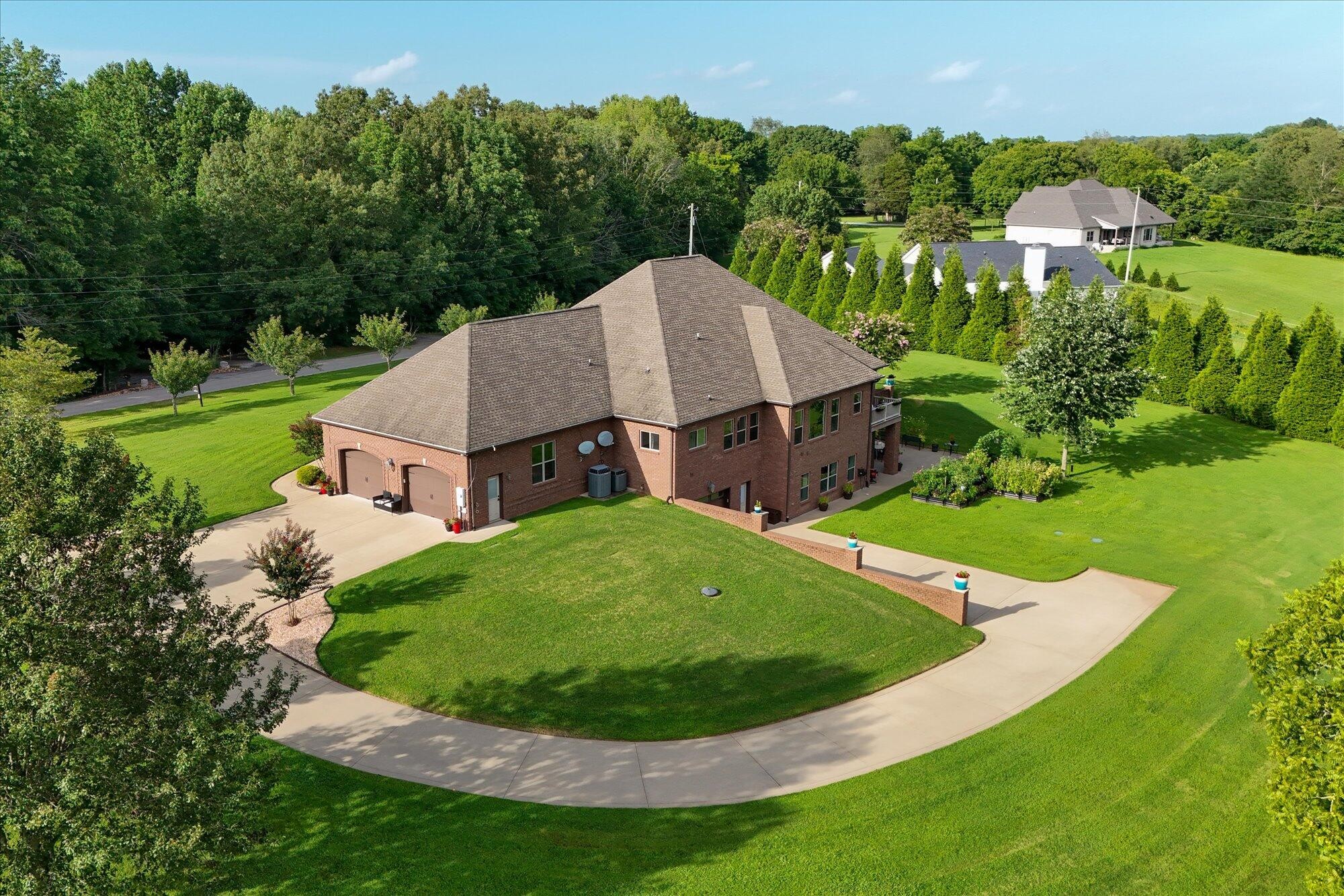 PRIVATE 5-ACRE ESTATE • CUSTOM ONE-OWNER HOMESet on 5 private acres in Adams, this custom all-brick home features 4,500+ sq. ft. of finished living space and approximately 6,900 sq. ft. under roof, with exceptional craftsmanship and flexible multigenerational living.Everything needed for everyday living is conveniently located on the main level. Every main-level bedroom features a walk-in closet, while the primary suite features two entrances and a double tray ceiling. Continuous real hardwood flooring flows seamlessly from room to room for a clean, custom-finished look. Distinctive custom millwork and trim throughout provide architectural detail rarely found in newer construction. The main living room features a beautiful custom coffered ceiling.The main kitchen includes double ovens, wine refrigerator, pull-out cabinet drawers and a large pull-out spice cabinet.The lower-level suite includes its own kitchen, laundry room, living space, walk-in tile shower and plank tile flooring—well suited for extended family, guests or multigenerational living.Additional highlights include two kitchens, two laundry rooms, two garages, foam insulation throughout, durable polyaspartic flooring in the upper garage, dual fuel, a 1,000-gallon underground propane tank, security system, sprinkler system, composite decking, plus utility sinks and heaters in both garages.Enjoy 5 private acres, mature landscaping and established garden areas with NO HOA and NO CITY TAXES.Located in the Kirkwood school zone with convenient access to Clarksville, Fort Campbell and Nashville.