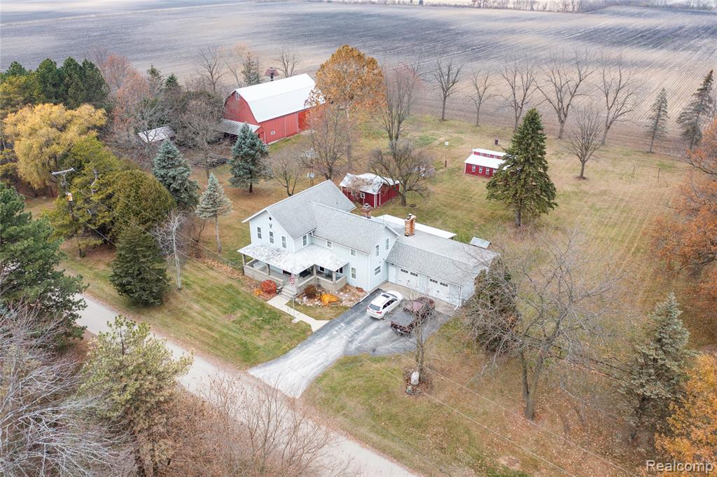 This beautiful late 1800s farmhouse, with 4 bedrooms, is what you've been waiting for! Situated on 4.23 acres with 5 outbuildings + an oversized attached garage, you'll have plenty of room! Featuring large covered front porches, invite your guests into the expansive kitchen that showcases the beauty of the 1800s, paired with updated & modern conveniences (SS appliances new in '22), with space for a table & chairs. From there, step into the spacious family room & cozy up to the wood burning stove, surrounded by gorgeous handcarved wood beams. Adjacent to the kitchen is a separate dining room, with a 9' x 5' bay window, overlooking the backyard. Off the dining room, there is a library/den, perfect for an office, hobby room, or non-traditional 1st floor bedroom (no closet). To the front of the home, you'll find the living room with access to the front porch, stunning wood ceiling beams, & a brick accent wall. As you take in all that this home has to offer, you'll notice the tall 8 ft tall ceilings, interior wood doors with skeleton keys, antique light fixtures, & the original wood staircase bannister & trim along the steps & into the 2nd floor. Upstairs is the updated master bedroom with attached full bathroom & walk-in closet. You'll find 3 more bedrooms on the 2nd floor, all with original wood flooring. Not to be forgotten is the 1st floor laundry, 2nd full bathroom (1st floor), & MI basement (w/ext Bilco doors) & crawlspace. The largest of the outbuildings is the 2600 sq ft hay barn, w/cement floor, stalls, & silo. There is also a 738 sq ft wood shed w/cement floor (cut wood inside stays), a 461 sq ft shed w/cement floor, a 245 sq ft grainery w/elevated wood floor, a 10-chicken coop w/3 nesting boxes & run, & an old little smokehouse. HVAC is forced air heat & AC, powered by a heat pump, w/propane backup (2020). (Excluded from the sale: garage refrigerator, basement freezer, firewood pile in front of hay barn--data & measurements approximate & not guaranteed).