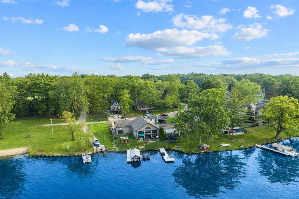 Move-in ready on all-sports Rush Lake, this exceptional waterfront residence offers 63 feet of pristine frontage and over 2,240 finished square feet of thoughtfully designed living space, perfectly positioned to capture sweeping lake views from every angle. A grand foyer with custom mudroom built-ins welcomes you into the heart of the home, where soaring vaulted ceilings and dramatic floor-to-ceiling windows create a light-filled, open-concept living area that seamlessly connects to the outdoors through expansive doors leading to the deck. The stunning kitchen showcases rich cherry cabinetry, a striking glass tile backsplash, abundant storage, and a beautifully accented center island featuring a built-in wine bar--ideal for entertaining. The main-level primary suite offers comfort and privacy, complemented by a spacious bathroom complete with dual sinks and a soaker tub.Also on the main level, you'll find a conveniently located laundry area with an adjacent custom dog wash station for added functionality. Upstairs, a lofted flex space, perfect for an office with a view or a family room, overlooks the main living area and is accompanied by two additional bedrooms and a well-appointed full bathroom. The space above the garage provides excellent storage or potential for future expansion. Significant updates include a new roof (2023), new tankless water heater (2024), completely repaved driveway (2025), fenced yard (2025), added storage shelving (2026), plus a 7-year-old furnace, A/C, and well. Additional premium features include an automatic whole-house generator, reverse osmosis system, air tub, remote-control blinds, lake-fed sprinkler system, additional parking pad, storage shed, and a two-car garage with an additional lake-side access door. Outdoors, enjoy privacy-enhancing greenery along with two docks included in the sale, offering generous space for boating, swimming, and fully embracing the Rush Lake lifestyle. Ideally located near Rush Lake Hills Golf Club, the Lakelands Trail, and convenient shopping, this