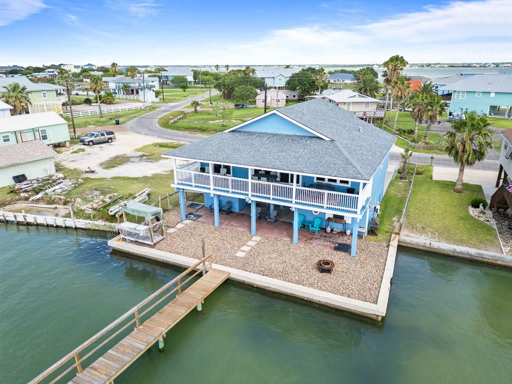 Experience the ultimate waterfront escape in this fully furnished coastal retreat with a proven short-term rental history and exceptional income potential. Designed for unforgettable memories, world-class fishing, and effortless entertaining, this property is the perfect investment, vacation home, or personal waterfront getaway. Upstairs, you'll find three spacious bedrooms and a bright open-concept living, dining, and kitchen area. Vaulted ceilings and oversized sliding glass doors create a light-filled atmosphere while showcasing stunning waterfront views. The expansive covered patio spans the length of the home, providing the perfect place to enjoy morning coffee, evening cocktails, spectacular coastal sunsets, and frequent dolphin sightings right from your backyard. The well-appointed kitchen features white cabinetry, stainless steel appliances, generous counter space, and a large island that naturally gathers friends together. Multiple dining and seating areas make entertaining large groups easy and comfortable. Downstairs, a separate bunkhouse with its own half bath offers a fun and flexible space for guests & fishing buddies. This unique bonus area adds versatility and charm while maximizing sleeping accommodations. The true highlight of the property is the impressive 225-foot private pier (completed 10/2024) extending into prime fishing waters. Whether you're casting a line before sunrise, cleaning the day's catch at the fish-cleaning station, tying up your boat, launching kayaks, or simply relaxing over the water, this pier is built for the coastal lifestyle. From incredible fishing and boating access to breathtaking sunsets, dolphin watching, and strong rental performance, this waterfront retreat offers the perfect blend of comfort, adventure, and investment opportunity. Come relax, catch fish, make memories, and experience the very best of coastal living.