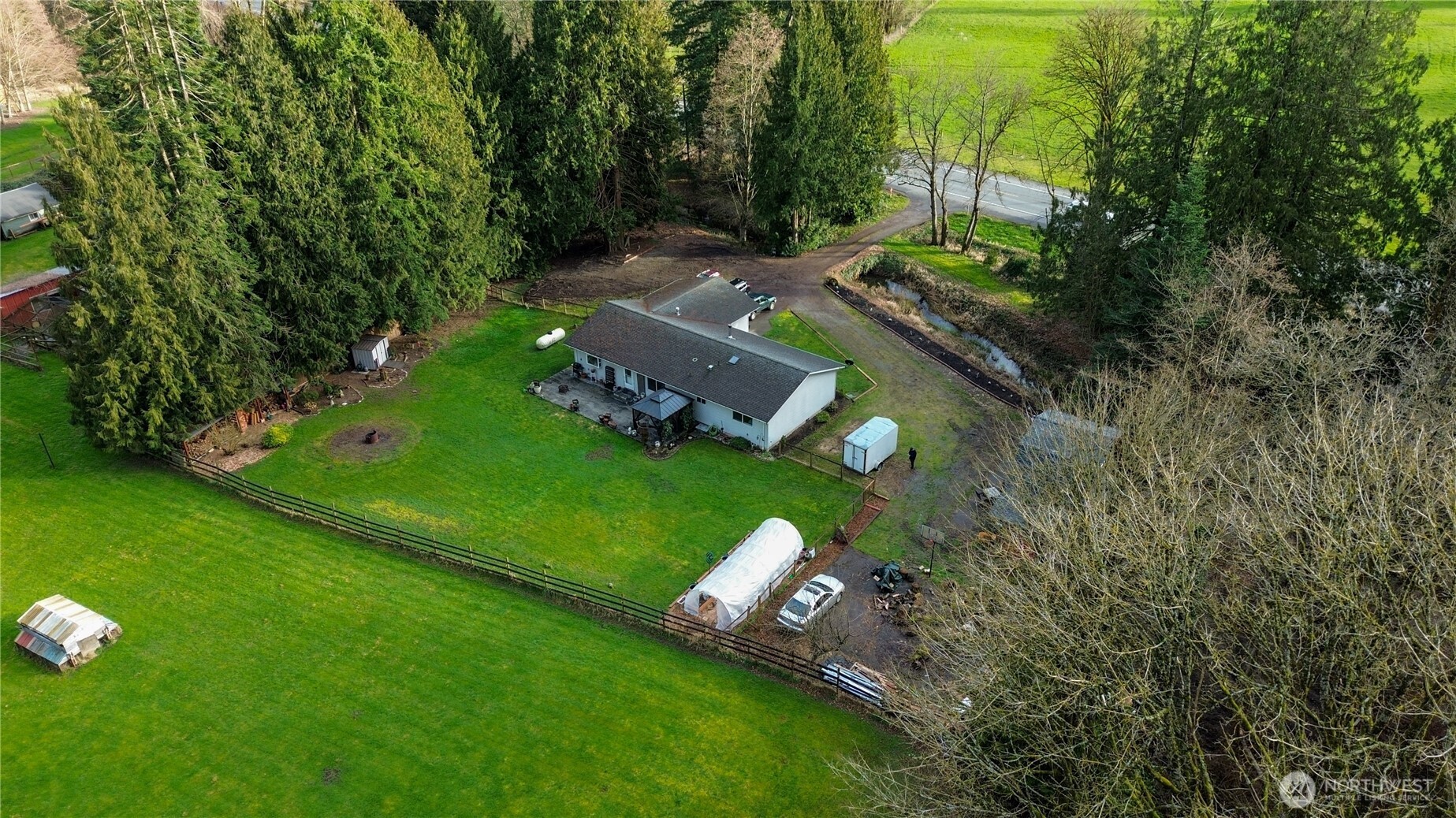 Discover the charm of County living with this warm and inviting 3-bedroom, 2-bath home. Offering 1,526 square feet of comfortable space, a 2-car garage, a shed, a detached outbuilding, and a flat, usable .74-acre lot, this property provides the perfect setting to enjoy, gather, and grow. Don't miss the opportunity to make this exceptional residence your new home.     Open-concept layout connects the living, dining, and kitchen areas for easy everyday living and entertaining. Spacious kitchen features abundant cabinetry, generous counter space, stainless steel appliances, bar seating, and warm wood finishes. The main living area is filled with natural light, while the forced-air propane furnace and freestanding wood-burning fireplace provide year-round comfort.     The fully fenced backyard is ready for enjoyment with a stamped concrete patio, gazebo, garden space, greenhouse, fire pit area, and beautiful mountain views. The patio includes wiring as an added convenience for future outdoor use such the addition of a hot tub or building an outdoor entertainment center.     With ample RV and off-street parking, it provides space for vehicles, guests, and recreational equipment.     The detached outbuilding with water and power offers exceptional versatility for storage, hobbies, workspace, or other possible uses, subject to buyer verification.     Enjoy the peaceful feel of country living just minutes from schools, trails, and everyday amenities.