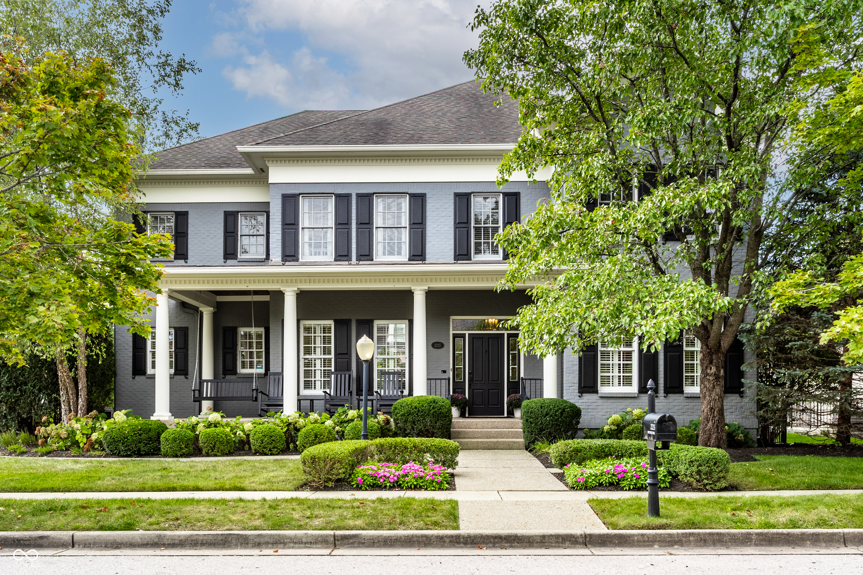 Welcome to 2225 Finchley Road, a former show home on one of the Village of WestClay's most beautiful tree-lined streets. Custom built by Kurt Schmadeke, this 5-bedroom, 4.5-bath residence showcases exceptional craftsmanship, architectural detail, and premium finishes.    A stately painted-brick facade, mature landscaping, and a deep, columned wraparound porch create an impressive yet welcoming first impression.    Inside, extensive renovations created a more open, functional flow while preserving the home's architectural character. Wide-plank French white oak flooring from DuChateau by Jack Laurie extends across the main level and second-floor landing.    The renovated kitchen centers around an expansive quartz island and features Thermador appliances, two KitchenAid dishwashers, a drawer microwave, Scotsman pellet ice maker, glass-front transom cabinetry, and Zephyr ventilation. A large window frames the wooded backyard and fills the kitchen with natural light.    The owner's suite is a true private retreat with separate walk-in closets and an adjoining wellness room featuring a fireplace, built-ins, and beverage counter. Beyond it, a second spacious room offers flexibility for yoga, Pilates, exercise, meditation, a home office, or another private retreat.    The finished lower level offers a bar with wine cooler and refrigerator, exercise room, bedroom, full bath, spacious television area, and fireplace.    French doors open to an expansive screened porch overlooking the private wooded backyard. Custom acetate windows extend seasonal enjoyment, while a convertible gas-or-wood-burning fireplace adds warmth and ambiance.    Beyond the porch, a stone-paved gathering area with a circular lava-rock gas fireplace creates an intimate setting for entertaining or relaxing beneath the trees.    Ideally located in the Estates section of the Village of WestClay, the home is steps from Coxhall Gardens and minutes from West Park, with easy access to walking paths, green spaces,