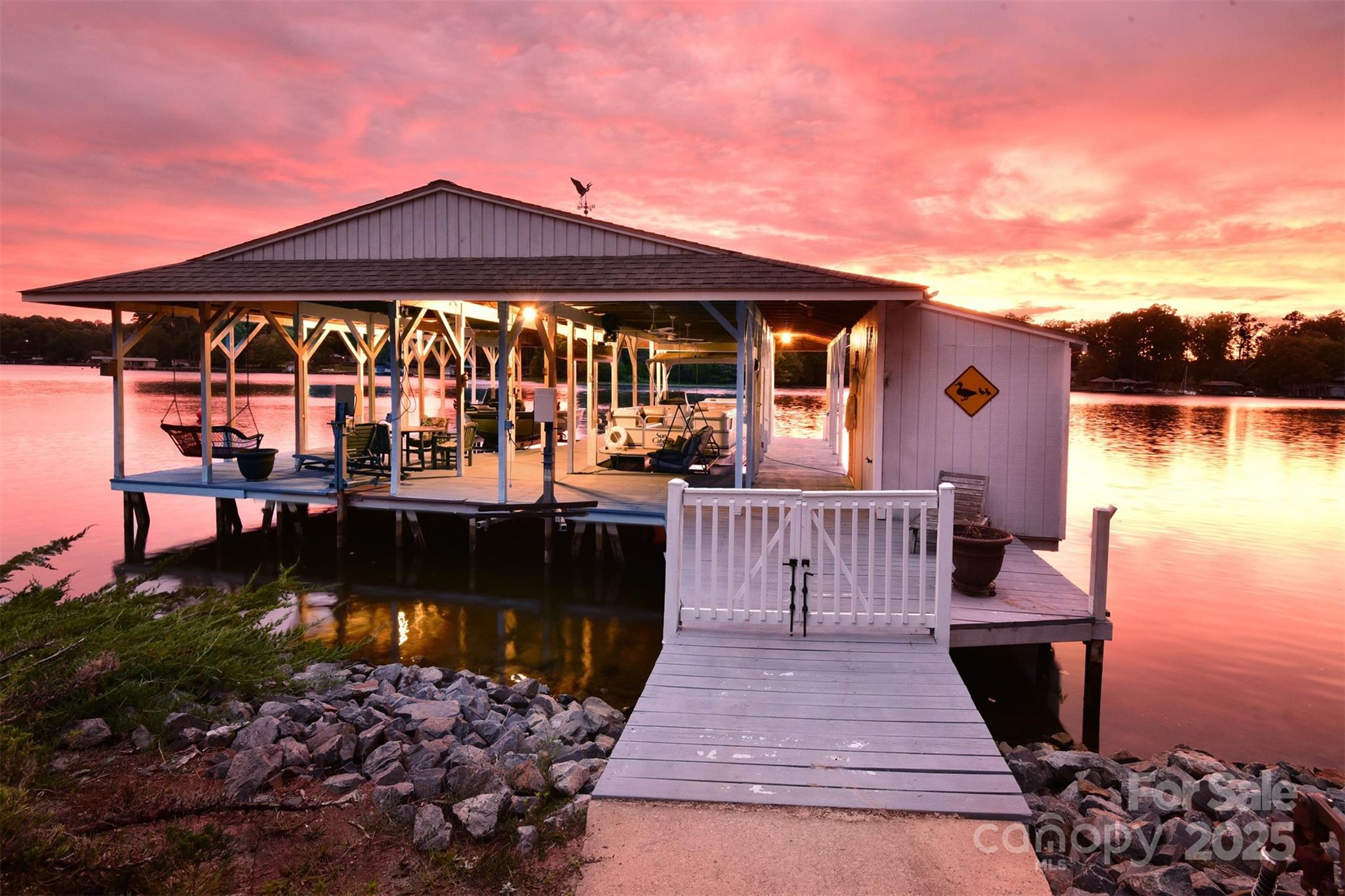 Welcome to your waterfront retreat on Lake Tillery! This warm and inviting home is filled with character, featuring cedar board siding and fir wood interior details. The two-story great room showcases a stunning stone fireplace with gas logs, perfect for gathering. Outdoors, the impressive boathouse offers two boat lifts, two jet ski lifts, and plenty of space to relax by the water. Rarely found features include a level lot, 2-car garage, and large 1,550+ sq ft boathouse with deep water. Enjoy the serenity of a peaceful cove while entertaining on the expansive back deck or in the spacious great room. Lake views can be found in almost every room of the home! This location is convenient to the local marina and waterfront restaurant. Home is being sold mostly furnished and includes the pontoon boat—move right in and start living lake life!