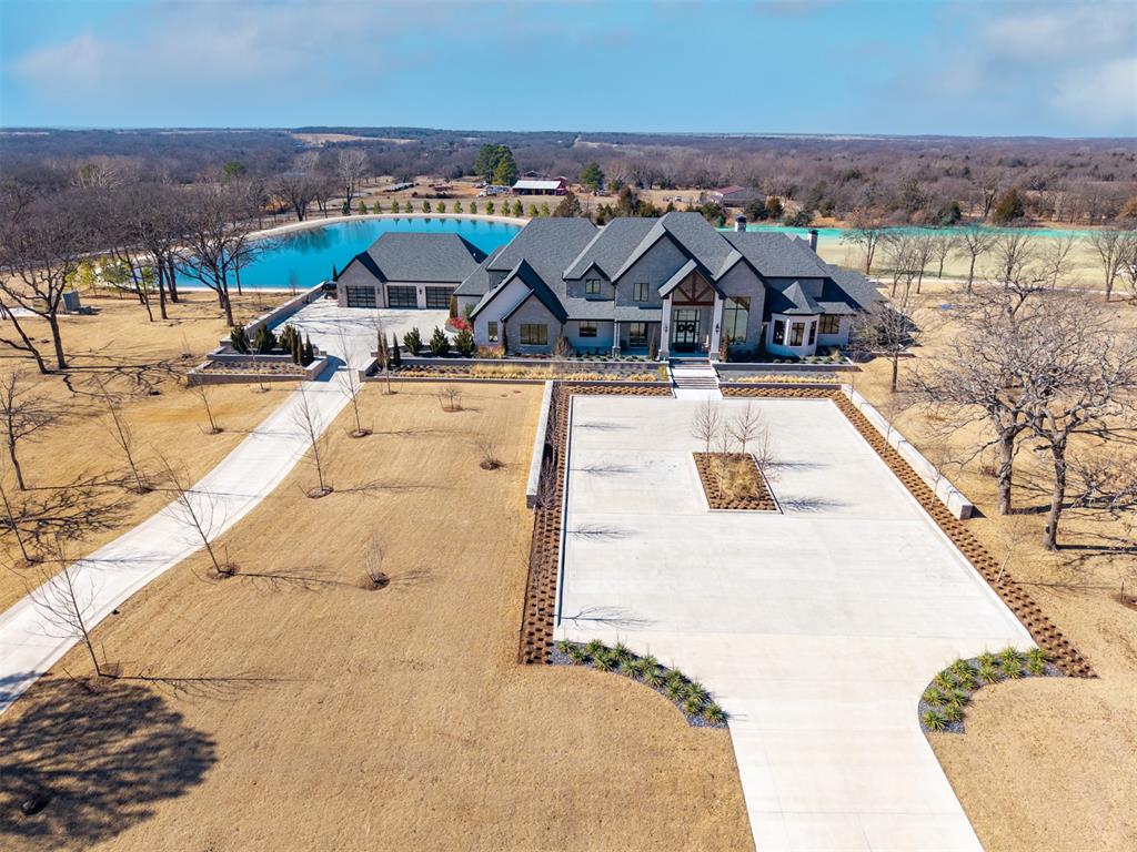 Set behind a sweeping private drive on 21.5 meticulously designed acres, this extraordinary estate delivers approximately 11,000 square feet of refined living space and over 15,000 square feet under roof. Architectural presence is immaculate, with layered rooflines, stone accents, and a motor-court style approach creating a commanding first impression.The 4-bedroom, 4.5-bath residence was built for elevated living and large-scale entertaining, featuring expansive gathering spaces, a grand wood-burning fireplace, private bar and game room, 16-seat theater, and a fully appointed butler’s kitchen. Smart home integration provides seamless modern control throughout.Outdoor living rivals private resorts. A pool and hot tub anchor the backyard, complemented by a pergola pavilion with wood-burning fireplace. The professionally installed turf lawn features a custom putting green with bunkers, overlooking a 2-acre geothermal pond fully stocked with fish and surrounded by a curved walking path.Two large irrigation wells support the grounds, while a 6,000 square foot shop offers exceptional flexibility for collectors, equipment, or business operations.Rarely does a property combine luxury residence, recreational amenities, infrastructure, and privacy at this scale. This is a true legacy compound designed for those who expect excellence.