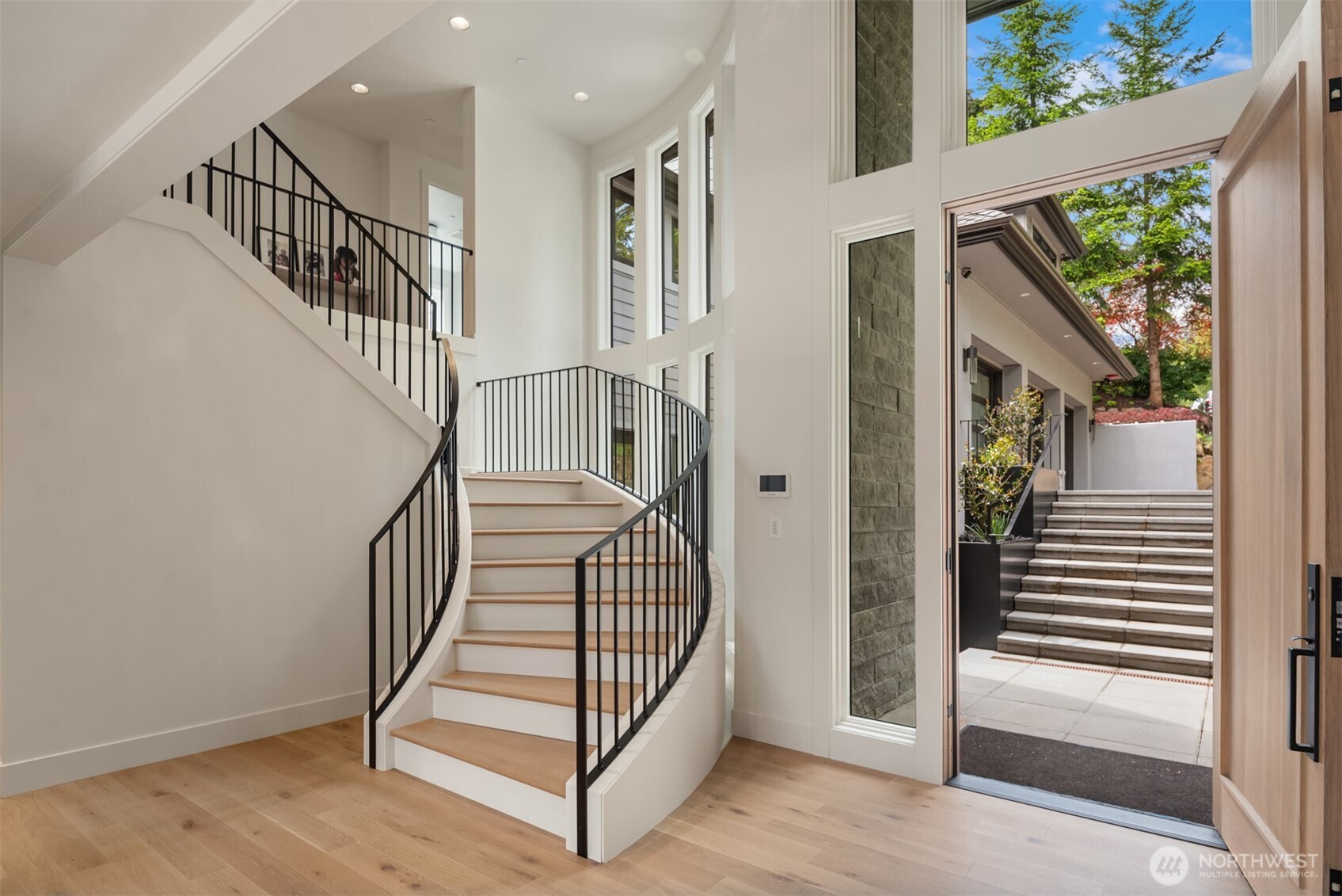 Grand entryway with soaring ceilings, sweeping staircase, and walls of windows that fill the space with natural light.