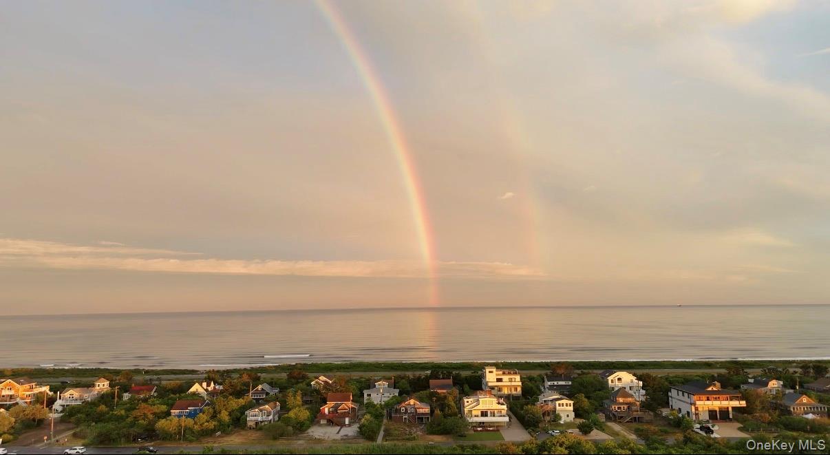 Welcome to West Gilgo Beach—a private, gated oceanfront and bayfront enclave of just 80 homes, situated between the Atlantic Ocean and the Great South Bay less than an hour from New York City. This secluded stretch of the barrier island offers something increasingly rare: space, quiet, and an intimate connection to the natural landscape, all while remaining easily accessible by car or the Long Island Rail Road to Wantagh Station, less than 15 minutes away. Private access to the ocean and bay means that much of the time, the shoreline feels almost entirely your own, with just the sound of the waves, the ocean breeze, the open sky, and the natural beauty of the island. Whether you envision it as a peaceful year-round residence or an idyllic retreat, the ever-present rhythm of the water creates a setting that feels less like a destination than a world apart—a place to escape, unwind, and call home.At the heart of this remarkable community stands 25 Ocean Walk, one of West Gilgo Beach’s last remaining original cedar-shake summer cottages. A living piece of Long Island history and one of the last surviving dwellings from the earliest days of the barrier-island communities, its story began at High Hill Beach, a summer colony settled around 1900 on the eastern edge of Zach’s Bay—a vibrant community of houses and a hotel that people traveled by boat across the bay to reach. In 1940, the cottage was carefully relocated five miles east to the newly planned and reconstructed community of West Gilgo Beach, where it has remained for more than eight decades, becoming part of a desirable and secluded neighborhood. Under the longtime care of its owner, who also serves as a devoted community historian, the home has been preserved not simply as a residence, but as an authentic piece of the shoreline’s past.Surrounded by mature pines, holly, bayberry, and native plants, it retains the unmistakable charm of an early beach cottage, with classic cedar-shake siding, rich knotty pine walls, and warm wood details throughout. There is a genuine spirit here that cannot be recreated. The main living level features a welcoming living room anchored by a traditional wood-burning stove, a light-filled family room lined with windows opening directly to the deck, alongside a separate dining room and kitchen. Three comfortable bedrooms and a full bath complete the main living area.Below, the home reveals the practical charm of a true beach house. An entry leads to two dedicated changing areas and a separate post-swim shower, thoughtfully designed for the easy transition from sand and saltwater to home. The space opens to a versatile open room with hardwood floors, brimming with potential and ready to be enjoyed in whatever way best suits its next owner. A workshop, half bath, and additional storage complete this level, while a standing-height attic with cross-ventilation provides exceptional additional storage and utility. Beyond the cottage, West Gilgo Beach offers a way of life that has become increasingly hard to find: a private barrier-island community with a strong sense of place and an enduring connection to the water. A private pedestrian underpass, only a few minutes’ walk from the home, provides seamless access to the ocean beach, while bayfront watercraft storage, docks, and a large swimming area make it easy to enjoy the Great South Bay.Community amenities include a marina with a waitlist, tennis and pickleball courts, a playground, a chapel/community hall, and a post office. For recreation and dining, the nearby Ocean Parkway Coastal Greenway provides a spectacular route for walking and cycling, while local favorites like Tobay Beach restaurants and splash park, the iconic Gilgo Beach Inn, the Jones Beach Boardwalk, and the Jones Beach Theater are just moments away. More than just a beach house, 25 Ocean Walk is a living piece of Long Island history—an authentic coastal retreat in a community that truly feels like a world apart.