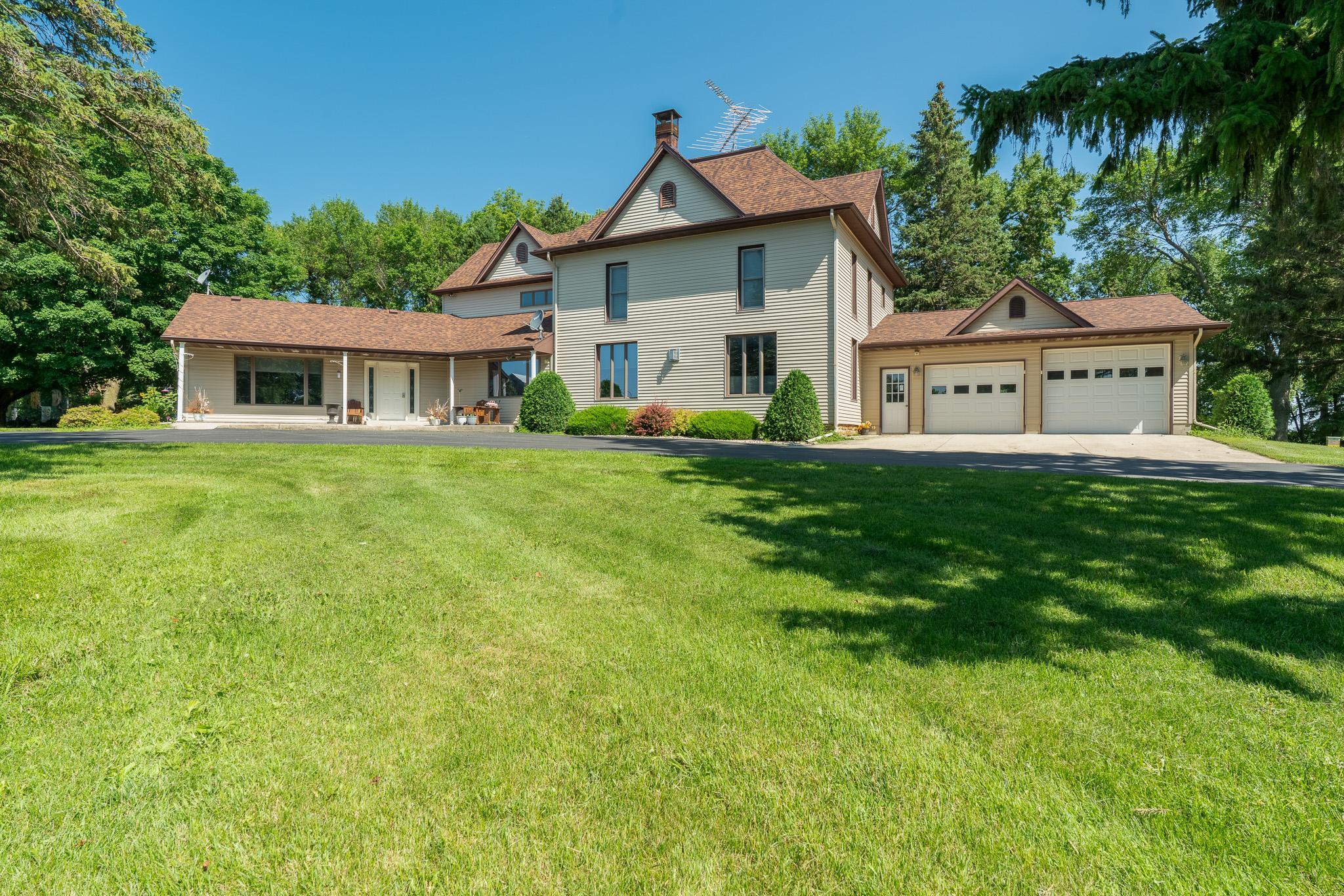 Dreaming of your paradise property?! This is it! Tucked into an absolutely picturesque setting with a tree-lined drive on 8+ acres offering landscaped sitting areas amongst the trees, gardens, and rolling lawn. This sprawling property with over 3800 square feet of living space must be seen to be truly appreciated. A spacious foyer welcomes you; to the left is the main living room w/pellet stove and a 4-season porch that takes you to the backyard. To your right is the dining room, kitchen with large center island w/granite & gas cooktop.  Off the kitchen you access a covered deck, aggregate patio, and a landscaped fire pit. Also on the main floor is a thoughtfully designed laundry room & pantry with ample storage and functionality, 3/4 bath & hot tub room. A craftsman-style living room with brick FP, rustic beams, cabinets & more make this an ideal place for gathering. The main-floor primary bedroom connects to a full bath with separate shower & tub + dual sinks and has a large walk-in closet. Head on up the main stair case and the 2nd floor brings 3 additional bedrooms, a full bath, and two rooms of closets and space for a playroom/craft area/reading nook...endless options to utilize it! Above the kitchen is the 5th bedroom (or nifty game room and bar) with 1/2 bath. The attached garage is heated with a 3rd overhead stall, great for toy storage, plus a framed out area that is currently used for workout space. A 45' x 72' shop with concrete floors and automatic overhead doors is perfect for just about any set-up.  This includes finished space for a heated workshop, and open space for vehicle/equipment storage.  A barn and granary (both with steel roofs) are a sign of the property's history, and are in nice condition. Add a paved basketball court, garden, patio, gorgeous views all around, and you've got your dream site! With compliant septic and numerous updates throughout, including steel siding, new 50-year roof (with transferable warranty) on the house, steel roofs on the outbuildings (2023), new pressure tank in well (2024), solid doors throughout the house, you'll appreciate the care that has gone into this property.