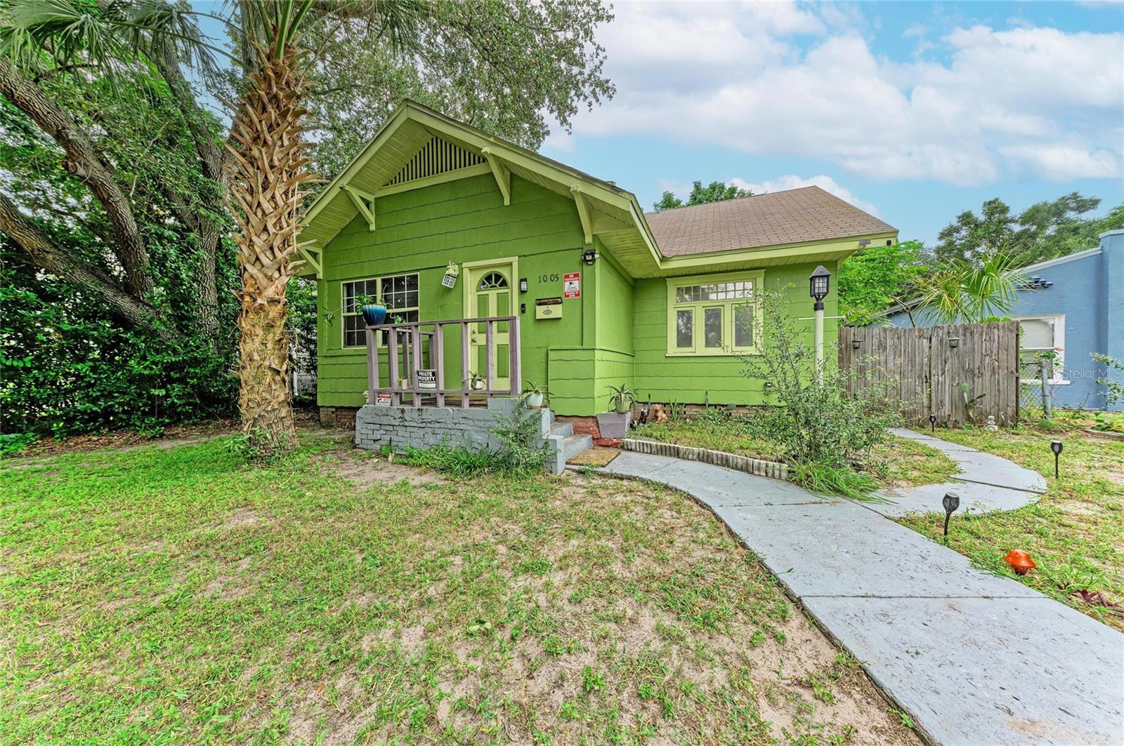 A 1925 Craftsman bungalow in Osborne Place with original hardwood floors, a coffered ceiling, a fireplace, and its built-ins intact, priced for the buyer ready to bring it back. Flood Zone X, a 50 x 130 lot with alley access, and minutes from Downtown St. Pete. The character is all still here. The front door opens onto an enclosed front porch with a beadboard ceiling and a wall of original windows looking into the living room. The living room has a coffered ceiling, paneled wainscoting, a fireplace with mantel, and a built-in bench. A Craftsman colonnade with built-in bookcases on both sides opens to the dining room, which carries the same wainscoting and hardwood floors. The main floor has two bedrooms and two full baths, including a bedroom with its own bath. The kitchen has wood cabinets and a long counter under a bank of windows, and a bright enclosed rear porch holds the laundry. Upstairs, the finished attic adds a third bedroom, a bonus room, and a half bath, with flexible space for an office, guests, or a studio. Outside, a stone-paver side path leads to a deep, fenced backyard with alley access and plenty of room for a garden, a pool, or future expansion (buyer to verify with the City of St. Petersburg). The home needs updating throughout and is being sold as-is, priced so the next owner can put that work in and keep the upside. You're minutes from Downtown St. Pete, the Edge District, I-275, and Tampa Bay, with Gulf beaches a short drive away.
