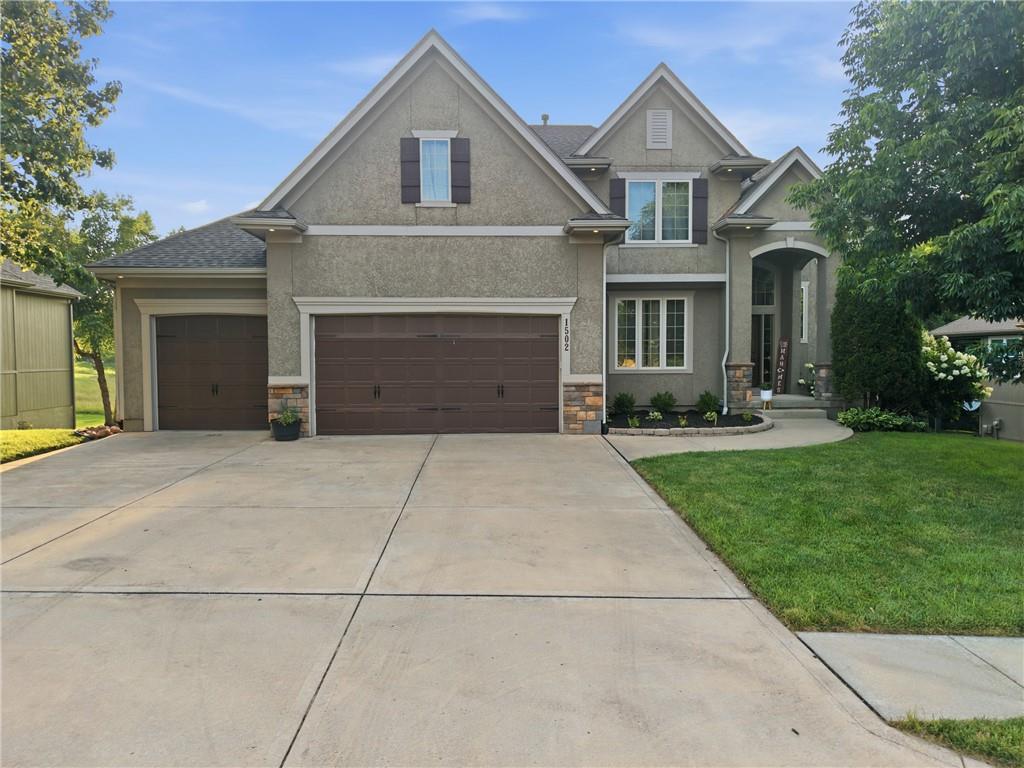 PRICE IMPROVEMENT TO $620,000!  STEAL OF A DEAL FOR THIS GORGEOUS, UPDATED HOME IN THE HIGHLY SOUGHT AFTER CREEKMOOR SUBDIVISION IN RAYMORE, MO! This stunning two-story home offers over 4300 sq. ft. of beautifully finished living space, five bedrooms and four and a half bathrooms.  From the moment you arrive, the stone and stucco elevation, manicured landscaping, and oversized three-car garage make a lasting first impression. Step inside to discover a grand staircase with ornate wrought iron balusters, rich hardwood floors, and a gorgeous great room complemented by a bold gas fireplace and large windows with beautiful views of the backyard!  The gourmet kitchen is a showstopper with granite countertops, custom cabinetry, new pendant lighting, an expansive island perfect for meal preparation and a huge walk-in pantry for ample storage.  A charming half bath with designer wallpaper is conveniently located just off the kitchen and adjacent to the well-appointed mudroom lending to the perfect drop zone as you walk in from the garage. New carpet on the main and second level accentuates this incredible home!  Four additional spacious bedrooms offer flexibility for family, guests or a home office.  The primary suite is a true private retreat, featuring dual vanities, a corner jetted tub, a walk-in shower, and a massive walk-in closet. The finished walkout basement takes this home to another level with a stylish wet bar, recreation room, full bath, and a fifth bedroom. Step outside to the freshly stained deck overlooking the treed backyard and the fourth hole of the golf course. Below, the flagstone patio with a firepit creates the perfect setting for evening gatherings. Situated in the amenity-rich Creekmoor community, this ERS-certified energy-efficient green home offers both luxury and sustainability. ****IN ADDITION TO THE PRICE IMPROVEMENT, THE SELLER IS OFFERING A $5000 BUYER CREDIT TO USE AT THEIR DISCRETION - PAINT, CLOSING COSTS, BUY DOWN, ETC.****