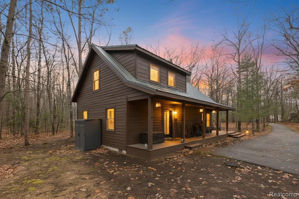 Discover your own private retreat on 5.8 serene acres. This secluded 3-bedroom, 2-bath home features stunning vaulted ceilings, rich wood floors, and a grand stone fireplace that anchors the open-concept living space. The kitchen offers granite countertops, stainless steel appliances, a butcher block island, and plenty of workspace—perfect for everyday living or entertaining. The spacious primary suite includes a beautifully appointed bathroom with a double vanity and a walk-in shower. Enjoy peaceful mornings on the covered front porch, or unwind in the tranquil wooded backyard complete with a fire pit for cozy evenings under the stars. A spacious pole barn provides exceptional storage or hobby space. This is the ideal blend of comfort, privacy, and Northern Michigan charm—your getaway awaits. Partially Furnished - Deeded Boat Dock access