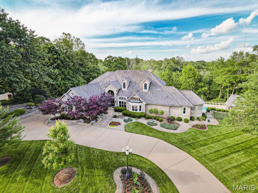 Live on Monday July 14th! Nestled on a 9.31-acre estate in Edwardsville, this luxury property exudes sophistication. The stone & brick facade, circle drive, extensive landscape & three-car garage create a grand entrance. Boasting over 6400 sq ft, the interior features a stunning entry & staircase, wood flooring, a main-level master suite, hearth room, great room & an office. The upper level is stunning with 2 en-suite bedrooms and a remarkable sitting area. The outdoor space is an entertainer's paradise, with a heated inground pool, outdoor kitchen, multiple decks/patios and wooded privacy. Equipped with a whole-house generator, this residence ensures uninterrupted living. An improvement list is available upon request, showcasing the property's many enhancements by current owner. This Edwardsville gem seamlessly combines elegance, functionality, & comfort; offering a rare opportunity for refined living in a tranquil setting. Near interstate access, dining, & shopping. 3 parcels total the 9.31 acres. Roof 2016. Additional Rooms: Wine Cellar