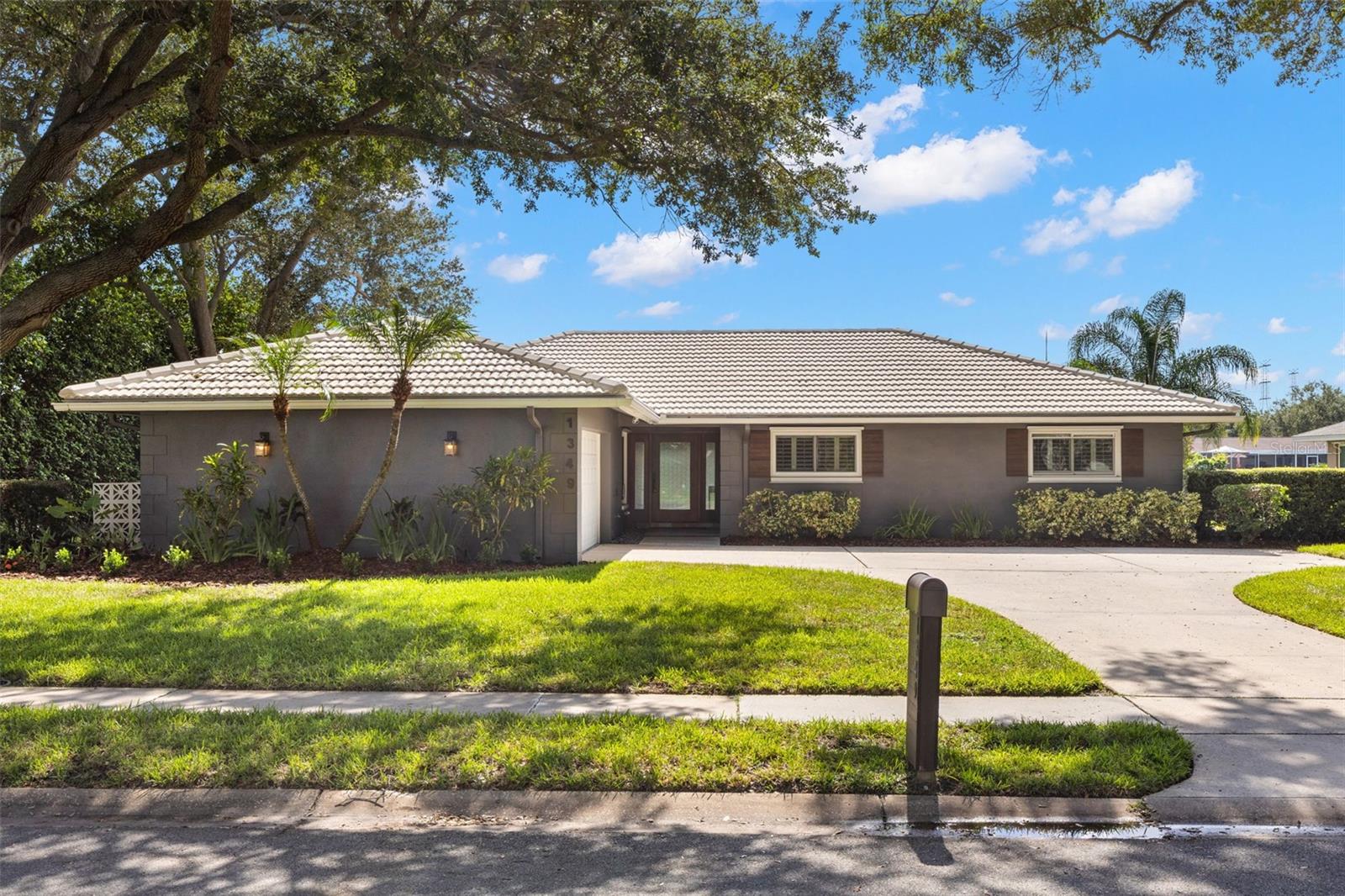 LAKEFRONT LIVING: At this Morningside lakefront home, the living space doesn’t stop at the back door-it continues through a 36-foot covered lanai, screened pool, and open patio to the water’s edge of Stewart Lake. Set on a generous .45-acre lot in Morningside Estates, this single-story 3-bedroom, 3-bath home offers 2,042 square feet of thoughtfully arranged living space, with mature trees, tropical landscaping, a tile roof, a circular driveway, and a side-entry two-car garage, creating an inviting first impression.Inside, the custom glass-paneled front door and textured sidelights introduce a home with personality rather than pretense. Wood grain tile and ceramic tile flooring define the main living areas, while plantation shutters, updated lighting, and a soft neutral palette keep the interiors relaxed and polished. The central living room steps down from the foyer and opens directly to the lanai through wide sliding glass doors. A separate family/bonus room, tucked behind French doors, offers a second gathering space with its own direct connection  to the lanai through wide sliding glass doors. New A/C 2024 and new Hot Water Heater 2025.The kitchen is a standout for anyone who actually likes to cook: abundant solid-wood cabinetry, expansive stone counter space, a subway-tile backsplash, dual ovens, stainless-steel appliances, a wine refrigerator, dedicated wine storage, and a raised breakfast bar that keeps conversation flowing between the kitchen and dining area.The primary suite is unusually spacious, with a carpeted raised sleeping area, room for a sitting or dressing area, plantation shutters, a walk-in closet, and an ensuite bath with stone counters, sleek cabinetry, and a glass-enclosed shower with a built-in bench and handheld showerhead. Two additional bedrooms feature carpeting, ceiling fans, and plantation shutters, with Bath 2 nearby, featuring a stone-topped vanity, makeup area, tub/shower combination, and built-in storage.Storage is a recurring theme here, from the long hallway with multiple closets and built-in drawers to the garage, where an expansive wall of cabinetry, a separate full bath, a laundry area, and a utility sink add real everyday function.Then there is the backyard-the part of the home that changes the rhythm of the day. A beamed covered lanai with statement lighting and a built-in brick grill opens to the screened pool (new pool cleaner 2026; newer pool pump 2024) and paver deck, while a large open patio creates a second outdoor living area. Beyond it, a broad lawn slopes gently toward the seawall and wide views across Stewart Lake. Enjoy the bonus using the lake water to irrigation your yard. Morning coffee, dinner outside, an afternoon swim or simply sitting still for a while all make sense here.Morningside Recreation Complex is blocks away, with tennis, basketball, fitness, lap swimming and playground facilities, while Clearwater’s beaches, shopping, dining, both area airports and the greater Tampa Bay region are all within easy reach. This is a home with room to gather, room to retreat and a waterfront setting that gives daily life a little more breathing room.