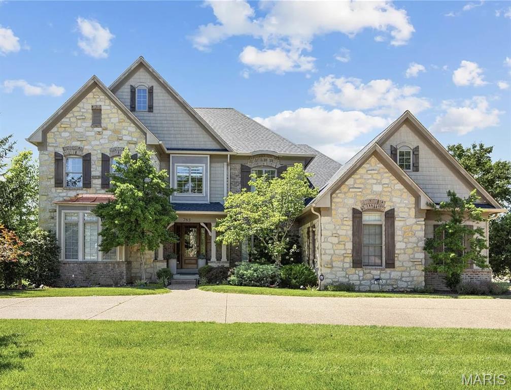 An impressive brick & stone elevation highlights the remarkable curb appeal of this spectacular 7079 sq ft 1.5 Sty. Exceptional craftsmanship and curated design elements including soaring ceilings, arched entryways, detailed trim work & oak hardwoods create effortless comfort and livability. The covered porch entrance with 8’ oak front door leads to welcoming foyer highlighted by dramatic flared staircase, private study with 8’ frosted glass double doors and formal dining room. A 12’ box beam ceiling, cast stone fireplace & expansive wall of windows set the tone for the stunning great room. Culinary enthusiasts will love the designer kitchen with custom white cabinetry, granite countertops, butler's pantry, 8’ center island & convenient planning center. The light-filled breakfast room and vaulted hearth room with wide arched entryway framed by architectural columns & stone fireplace provide an ideal gathering place. The spacious primary bedroom suite offers an appealing retreat with walk-in closet & beautifully appointed bath with jetted tub. Front & rear staircases access gallery landing surrounded by 3 additional bedrooms, 2 with Jack n' Jill bath, & hall full bath plus step-up bonus room. Lower Level entertainment space includes recreation room, game room, office & full bath. Situated on parklike 1.2-acre grounds with composite deck, hot tub deck, circular drive & 3-car garage.