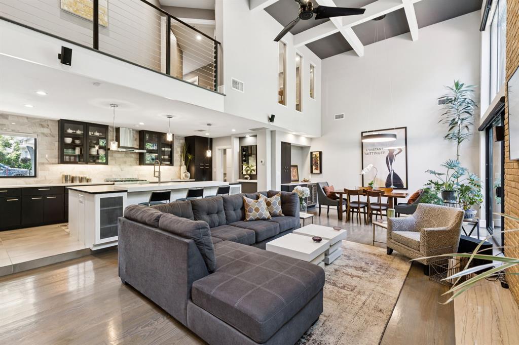 Living area with beamed ceiling, ceiling fan, light wood finished floors, beverage cooler, and a high ceiling