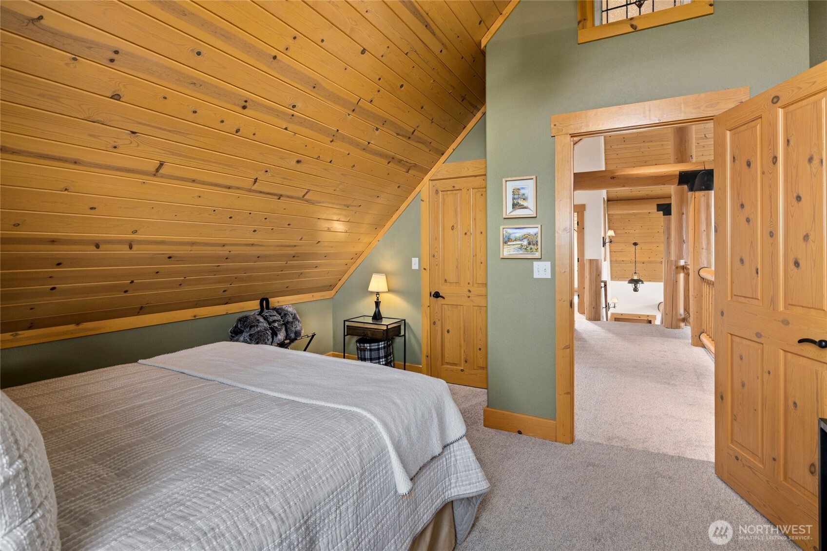 Upper-level guest bedroom featuring a distinctive wood-clad ceiling and warm natural finishes.