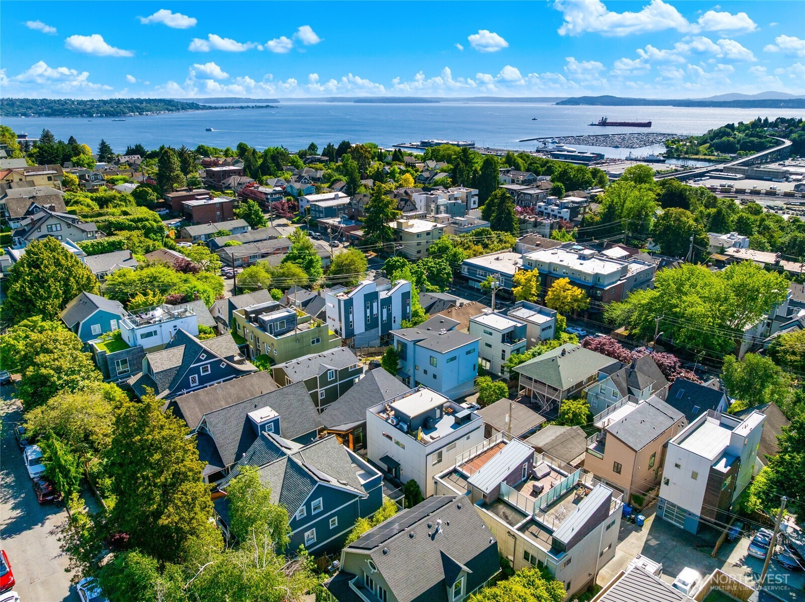 Opportunity knocks! Nestled on a quiet tree-lined street on Queen Anne, this well-maintained corner townhome presents the ultimate in-city living experience. Built in 2017, this stunning urban home is flooded with natural light and checks all the boxes: great location, custom finishes, dream layout, views of Puget Sound & Olympics, and a private garage! Step inside to real hardwood floors, freshly painted interior, huge windows, and SW exposure. The main floor features a spacious chef's kitchen with gas cooking & quartz island, open concept living and dining, fireplace, powder room, and dramatic custom steel + glass floating staircase. Retreat to a top floor primary suite with water views and walk-in closet. Inviting guest suite on lower level features heated concrete floors and private bath. Enjoy breath-taking views of Puget Sound and Olympic Mountains from the huge rooftop deck, perfect for relaxing in sunshine and entertaining. Additional features include AC, ample storage, large attached garage plus an additional off-street parking spot. A townhouse with 2 parking spots on QA is almost unheard of! Conveniently located near neighborhood shops, restaurants, parks, and excellent schools. Close to downtown Seattle, South Lake Union, and more. New price - incredible value.