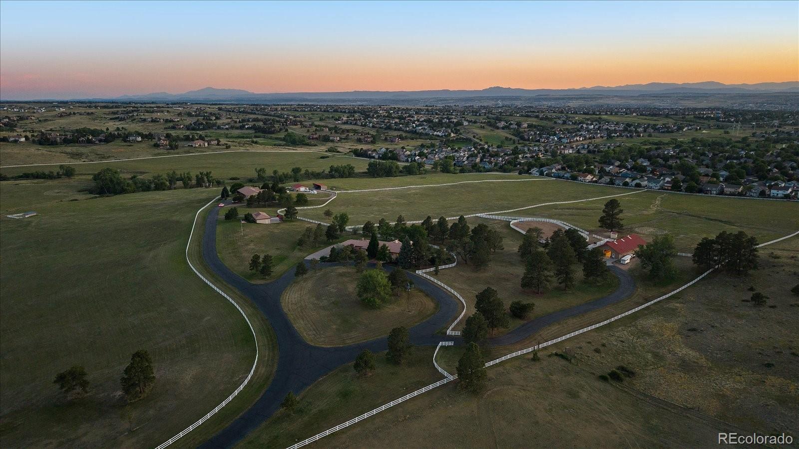 An extraordinary opportunity to own two homes and two barns on 53 acres of Colorado countryside with a significant 142 acre feet of water rights, just ten minutes from downtown Parker. Combining two distinctive residences, premier equestrian facilities, versatile outbuildings, and breathtaking natural surroundings, this rare offering is ideal for a private family compound, multigenerational living, or luxury equestrian retreat. Rolling hills, mature trees, picturesque gulches, sprawling pastures, and panoramic mountain views create a spectacular setting. The custom Zen Mission-style main residence showcases timeless architecture, a dramatic barrel-vaulted ceiling, Dover cedar windows, wood plantation shutters, and solid wood doors. The gourmet kitchen features Sub-Zero, JennAir, and Bosch appliances, wet bar, and walk-through pantry. A luxurious primary suite offers a striking Latilla ceiling, fireplace, spa-inspired bath, and French doors to a resort-style backyard with heated lap pool, newer hot tub, and generously appointed outdoor entertaining areas. Multiple workspaces, fitness room, and four-car garage complete the home. The heated Morton-built barn features seven 12x12 stalls with individual runs and automatic waterers, plus heated office, kitchen, bathroom, feed, and tack rooms. An outdoor riding arena, fenced and cross-fenced pastures, and water hydrants provide exceptional equestrian functionality. A separate Southwestern-style guest/caretaker residence offers three main-level bedrooms, including a spacious primary suite, plus a finished lower level with private exterior entrance, full kitchen, living area, bedroom, and bath. Ideal for extended family, guests, or on-site staff. Additional outbuildings accommodate horses, equipment, and recreational storage. Incredible water rights included. Two residences, 52.97 expansive acres, established equestrian infrastructure, and an unparalleled location create a rare opportunity for a Colorado legacy estate.