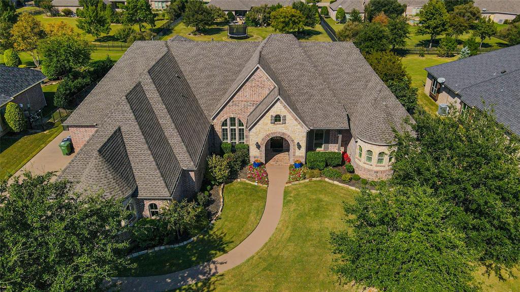 Imagine yourself coming home to this stunning custom-built residence, where every detail — from the hand-crafted finishes to the serene outdoor living spaces — reflects timeless Texas elegance and comfort. Built by award-winning custom builder Dave R. Williams, this home showcases exceptional craftsmanship and architectural design. The open-concept floor plan features 5 spacious bedrooms, 5.1 baths, a gourmet kitchen with an oversized island and walk-in pantry, and a vaulted family room with wood-beamed ceilings. Elegant groin ceilings, hardwood floors, and designer lighting create warmth and sophistication throughout. The primary suite offers a private coffee bar, dual walk-in closets, and a spa-inspired bathroom with a jetted tub and built-in vanity mirror. Enjoy movie nights in the media room or quiet mornings on the covered patio by the outdoor fireplace, surrounded by mature trees and lush landscaping. Additional highlights include Toto washlets in all bathrooms, an EcoWater softener system, a 3-car epoxy-floored garage, and a lightning arrestor for added protection. Located in the highly rated Prosper ISD, close to parks, dining, and top amenities — this is luxury living at its finest.