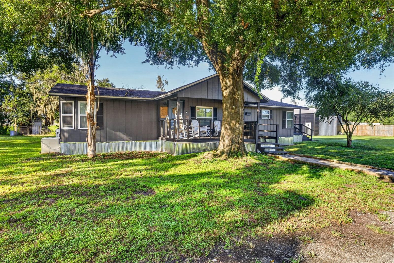 LOCATION***LOCATION***LOCATION***NO HOA***BRING THE BOAT, THE RV, ALL THE TOYS AND ALL THE ANIMALS***Welcome home to the perfect blend of country charm and modern convenience! A quaint covered front porch welcomes you inside, offering the perfect spot to enjoy your morning coffee, unwind in the evening, or simply take in the peaceful surroundings. This beautifully updated 3-bedroom, 2-bathroom home features a desirable split-bedroom floor plan designed for both comfort and privacy. The generously sized primary bedroom is privately situated away from the secondary bedrooms, creating a peaceful retreat complete with an en suite bathroom featuring dual vanities and a walk-in shower. The spacious family room serves as the heart of the home with a cozy wood-burning fireplace, while the separate dining room opens to a side porch, creating an ideal space for indoor-outdoor entertaining. Extensive updates provide peace of mind, including luxury vinyl plank flooring throughout (2026), metal skirting (2026), exterior paint (2026), freshly stained and sealed decks (2026), interior paint (2025), a new tankless water heater (2025), new refrigerator (2025), roof (2021), replacement windows (2021), a 300-foot deep well (2021), and a septic system pumped in 2021. The kitchen also features reverse osmosis water connected directly to the refrigerator for fresh, filtered drinking water.  Outside, you'll find endless possibilities with two oversized carports ideal for an RV, boat, side-by-side, or additional vehicles. A 25' x 30' metal barn with 11-foot doors and provides exceptional storage or workshop space, while the high-roof storage shed offers even more room for equipment and tools. The fully fenced property is secured with a solar-powered electric gate and includes two remote clickers for convenient access to the asphalt covered driveway. The privately fenced yard is ready for your country lifestyle with a charming treehouse and an enclosed pen that's perfect for livestock, goats, chickens, or creating your own backyard homestead for fresh eggs year-round. Best of all, there's no HOA, so bring your RVs, boats, trailers, work vehicles, and animals without restrictions.This property offers an incredible opportunity to enjoy peaceful country living while remaining just minutes from I-4. Conveniently located between Tampa and Orlando, you'll enjoy easy access to world-famous attractions, beautiful Gulf and Atlantic beaches, airports, shopping, dining, and medical facilities. Enjoy the best of both worlds—a quiet country setting with everyday conveniences just a short drive away. Come see this property for yourself and take in the peace and serenity that you can soon call home!