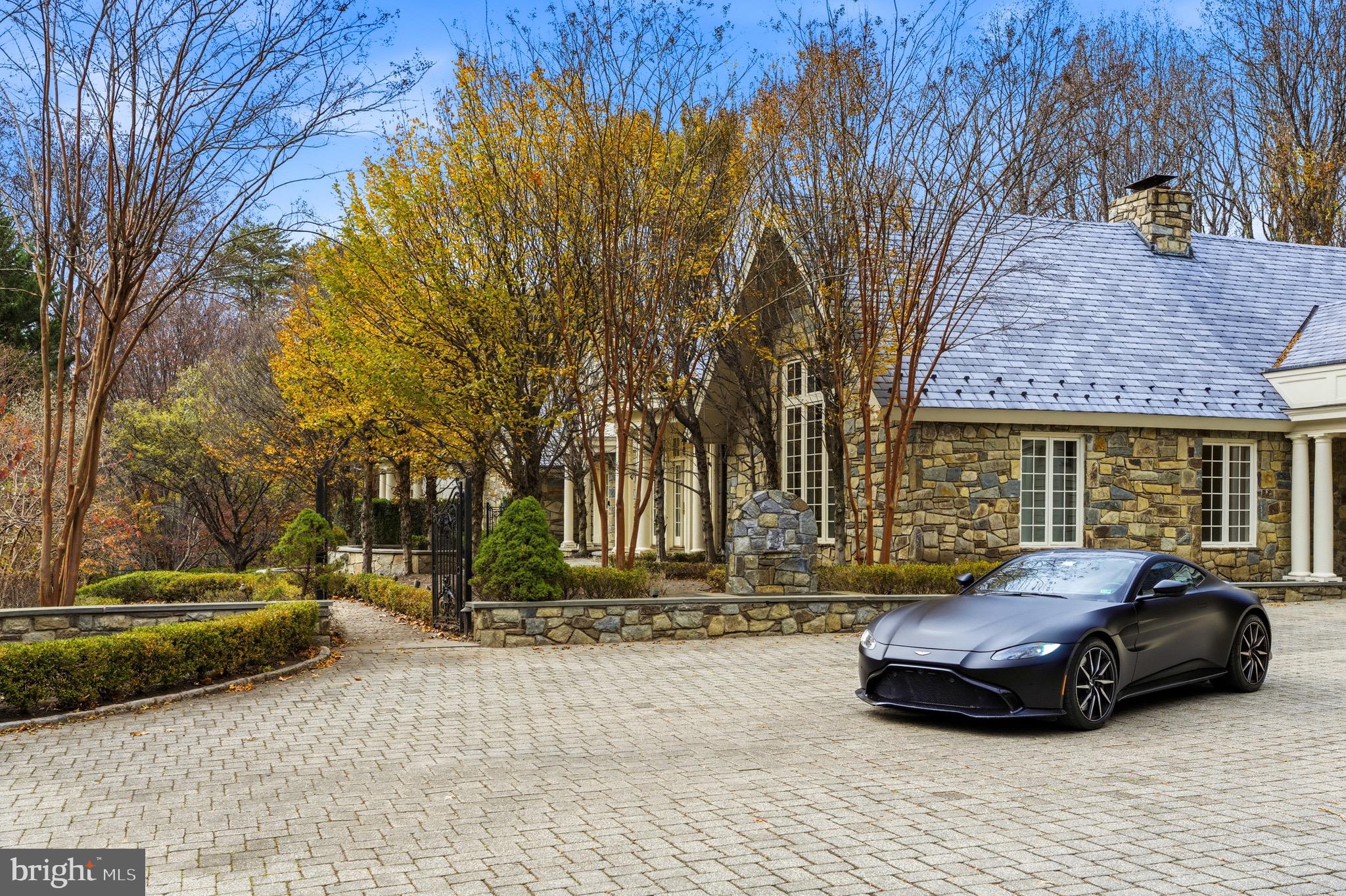 Welcome to Stone Wood, your private sanctuary. An enchanting tree-lined driveway winds through rolling greenery, guiding you to a timeless oasis set on over 5 serene acres. Originally crafted in 1984, masterfully expanded by renowned architect George Stavropoulos in 2000, and exquisitely reimagined in 2021, this estate blends classic grace with modern sophistication. Behind its gated entrance, the drive reveals a stately manor surrounded by manicured lawns, cascading fountains, vibrant gardens, and a tranquil pond beside a resurfaced large tennis court. A full gym and a beautiful guest house complete with its own kitchen further elevate the property’s resort-like appeal. Designed for both intimate living and grand entertaining, the interiors glow with natural light, showcasing intricate millwork, fine finishes, and six elegant fireplaces. The gourmet kitchen—anchored by custom cabinetry, chef-caliber appliances, and its own wood-burning hearth—flows into a cheerful breakfast room and a soaring two-story great room framed by walls of glass. The Versailles-inspired grounds, envisioned by landscape artist Charles Owen, enchant with stone fountains, French wrought-iron gates, and meandering pea gravel paths. Just minutes from Tysons Corner, McLean, Washington D.C. and Dulles Airport, Stone Wood offers refined living in a resort-like setting—an oasis of elegance, artistry, and tranquility.
