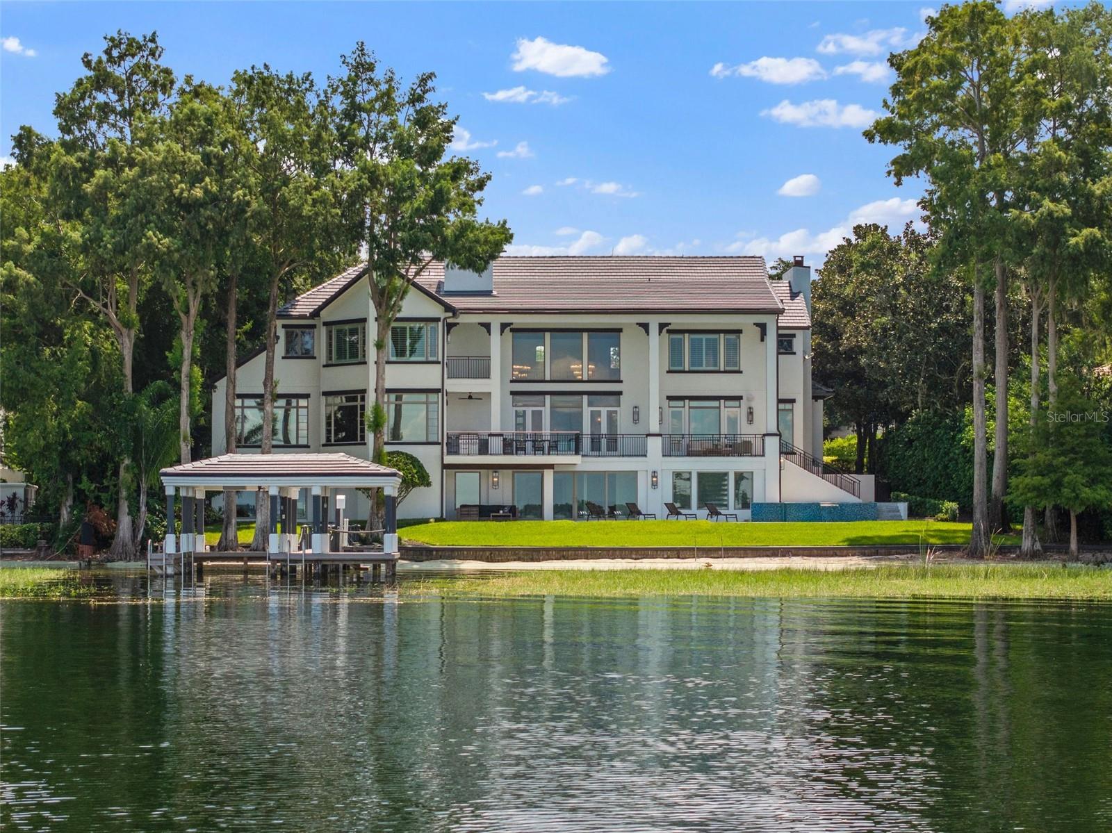 One or more photo(s) has been virtually staged. Introducing an exquisitely remodeled three-level Isleworth home on Lake Butler in the renowned Butler Chain of Lakes.  Boasting a spacious 11,100 square feet of luxurious living space, this magnificent residence features 6 elegant bedrooms, 7 full bathrooms, and 3 convenient half bathrooms. Designed for both comfort and entertainment, the home includes an array of premium amenities such as wellness and recreation; featuring a relaxing sauna, gym, and golf simulator. An entertainment and leisure lounge includes a full bar, spacious theater room and access to exterior lounge area.  The outdoor oasis is complete with a sparkling pool and hot tub, along with a fully refurbished dock with a brand-new boat lift.  Luxury finishes such as detailed millwork and crown molding throughout; a grand soapstone fireplace and premium quartz and marble surfaces round out the estates’ style and classy décor.
This home is not only a haven of comfort but also offers convenience with an elevator and breathtaking lake views. Embrace the bright, open spaces and modern elegance.  This stunning property is perfect for those who seek the finest in lakefront living.