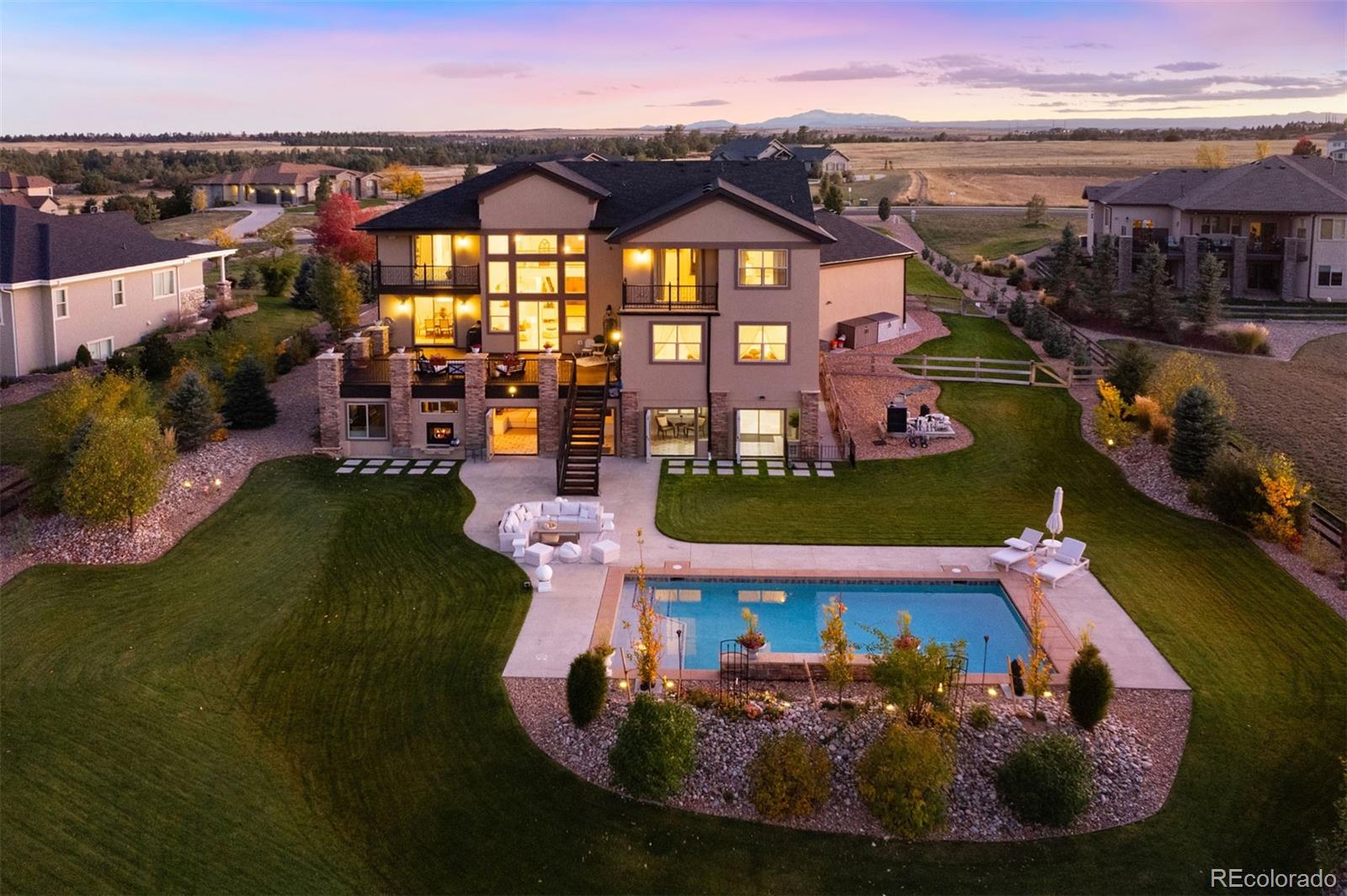 Every detail here has been elevated to live beautifully. More than $500,000 in recent improvements redefine this Castlewood Ranch Estates home as a true private resort. A heated saltwater pool with waterfalls and sun shelf defines the outdoor experience, framed by mature, estate-like landscaping, open space, mountain, canyon views, and the quiet privacy of a cul-de-sac setting. The fully enclosed all-seasons sunroom, with heated floors, a see-through fireplace, hot tub, and folding glass doors opens wide to the pool deck, creating effortless indoor-outdoor flow designed for gathering. Double doors welcome you into a grand entry with two-story ceilings, sparkling travertine tile floors, and an iron banister that draws the eye upward. Walls of windows fill the home with natural light and offer a view straight through to the deck beyond. The open layout blends everyday function with timeless design. A spacious kitchen with antique white cabinetry and a large island connects seamlessly to the great room with gas fireplace, as well as the formal living and dining areas. Upstairs, the primary suite offers a private balcony, custom walk-in closet, and a bath complete with a jetted soaking tub and oversized shower with dual heads and rainfall feature. Two additional bedrooms with private bathrooms and a flexible landing provide versatility, while a main-floor bedroom with adjoining bath serves as a guest or office option. Two laundry rooms add practical ease. The finished walkout basement expands the home’s livability with a large recreation room, wet bar, theater-ready space, and a dedicated area designed to accommodate a golf simulator setup. Extensive exterior upgrades, a newly expanded patio, upgraded garage cabinetry, refreshed lighting and bath finishes, and a four-car oversized garage with RV bay complete this meticulously improved Castle Rock residence.