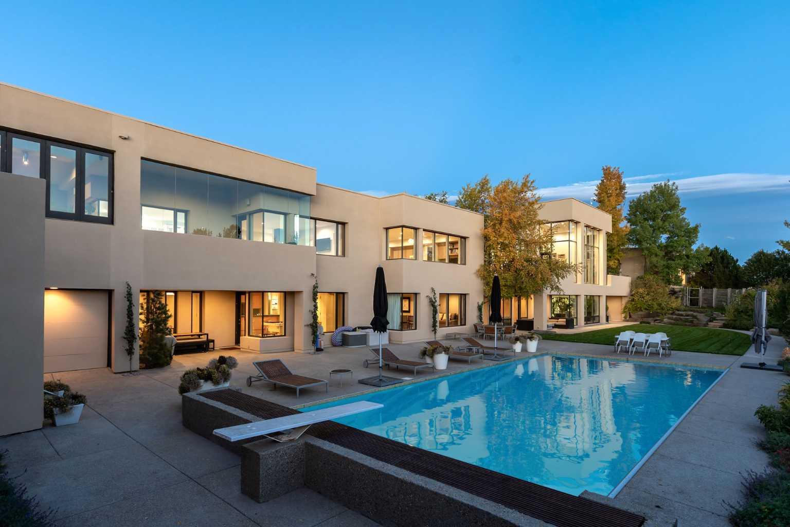 Seize a rare opportunity to own an iconic landmark in the prestigious southwest Springbank area, one of Calgary’s most coveted locations. Set on an expansive 18.62-acre escarpment, this exceptional property offers stunning mountain views and unparalleled privacy. Designed with new-age minimalism, this 20,000+ sq ft estate is a serene retreat for the discerning buyer. Located just minutes from Stoney Trail West, on the edge of Calgary, this secluded paradise offers the ultimate in luxury living. With 6 bedrooms + 10 bathrooms + 2 large offices, the home features stunning architectural design, including soaring flat & vaulted ceilings, a grand two-story great room illuminated by expansive windows. The contemporary living spaces are complemented by a soothing wood fireplace & ZEN garden inspired hallway views. The spacious dining room, perfect for memorable gatherings, overlooks beautifully landscaped grounds and majestic mountain vistas. Ample vehicle storage includes an oversized 3 car garage, a 2 car garage, and an additional oversized auxiliary 3 car garage (all heated). The gourmet kitchen is a chef’s dream, featuring a Wolf gas range with dual ovens, a built-in refrigerator, a walk-in pantry, an oversized granite island and custom white oak cabinetry. The adjacent family room includes a cozy fireplace, while the sunroom with another fireplace is perfect for family game or movie nights. The bedroom wing, secured by fire doors, houses the luxurious primary suite, a tranquil haven with views of mature trees and a lounge area with a fireplace. The ensuite boasts a deep soaker tub, granite dual-sink vanity, dual toilets, a bidet, and 2 oversized showers, along with a spacious walk-in closet. Four additional bedrooms, each with its own ensuite, are located in the bedroom wing, along with a laundry room and extra storage. Heated floors throughout both the main and lower levels provide year-round comfort. The lower level offers an additional bedroom with a full bathroom, a dedicated hot tub room, a spacious exercise room, an office and a large recreation room. A nearby bar and media room add to the entertainment space, while a walk-up entrance leads to the beautifully landscaped backyard, where a large in-ground pool awaits. Outdoor spaces include southwest-facing decks and a patio, a vast yard, and a middle courtyard with a sports court. An auxiliary building offers potential as a future guest house. The property has undergone millions of dollars in recent landscaping, with paved and natural pathways, waterfall features, and hidden sitting areas. Two security gates, fencing, and surveillance cameras ensure your privacy and security. This magnificent estate offers a private oasis with rolling hills, lush gardens, and elaborate landscaping that rivals anything in Aspen Hills—yet is only five minutes away from top-tier private schools. Experience the pinnacle of luxury living in Canada. Schedule your private tour today and discover all that your next home has to offer.