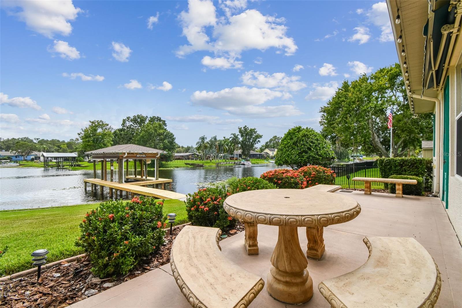 Custom Lake Saxon Home with Private Boat Dock. Boaters welcome!  Located in Lake Padgett Estates, Land O’ Lakes, Pasco County, Florida.  Built in 2006, this home is the perfect way to start your Lake Life.  It is also a perfect home to make your next move. You will have the freedom to enjoy Lake Saxon and mother nature on a daily basis.  Bring your pontoon, wakeboard, or other boat to keep safely covered in your boathouse with a lift.  Sunset cruises are spectacular.  Lake Saxon is a wonderful private lake that welcomes fishing, boating, skiing, kayaking, paddleboarding, and so many other recreational ways to live the Lifestyle.   This home boasts 4-bedrooms, 2.5-bathrooms, oversized 900 square feet-3 car garage with A/C workshop. This lakefront residence is a rare find—offering a lifestyle of waterfront serenity and luxury upgrades throughout. A screened front porch is perfect for catching the breeze during the cooler months.  French doors to the right open to a flexible office or guest bedroom, large enough for a desk, couch, and table—ideal for working from home. The great room features a charming stone fireplace and breathtaking views of Lake Saxon.  Large kitchen with bar seating, 42” Pecan cabinets with undermount and top lighting, center island will make cooking and serving food a breeze.  The primary suite offers an oversized room with lake views, access to the Florida room, 2 walk-in closets, dual sinks, and a shower. A concealed hallway creates a private feel for two guest rooms and a bathroom with a Jacuzzi whirlpool tub and shower.  Do you enjoy grilling comfortably?  Step into the Florida room with a custom grill and vent system.  Open the large slider and you can keep the room cool.  Outside is a large lanai with decorative stone tables and seating to relax and take in the day.  Two Sun setter roll-out awnings help reduce the temperatures during the warm season.  Want to keep your boat clean from the elements?  Drop your Sunsetter shades easily.  This garage has room for it all.  Up to two, 23’ boats with trailers parked inside the garage.  10’ wide garage doors and taller ceilings make it easy to park or back in oversized loads. In the back of the garage, you will find an air-conditioned workshop / man cave/ or any room you want to make it.  Room for a full-size fridge, 50-gallon water heater, water softener with holding tank with Reverse Osmosis at the kitchen sink.  Cabinets and lots of storage racks to keep all your tools organized.  Please see the attachment for the full list of upgrades.  This house is well with septic and drain field.  Lake Saxon is a private ski lake with tall Cypress trees that make for wonderful sunset cruises. Lake Padgett Estates is a tranquil community. They don’t build neighborhoods like this anymore. Ownership includes access to several ski lakes: horse stables (fees), parks, boat ramps, tennis and pickle-ball courts, and many other recreational activities. Located minutes from Land O' Lakes recreation center, schools, restaurants, Premium Outlet Mall, shopping, and other daily needs. 10 minutes from I-75, 15 minutes to the Suncoast Parkway, 35 minutes to Tampa Airport and 40 minutes to Sand Beaches. Peaceful sunsets and total relaxation await you here. Welcome Home!