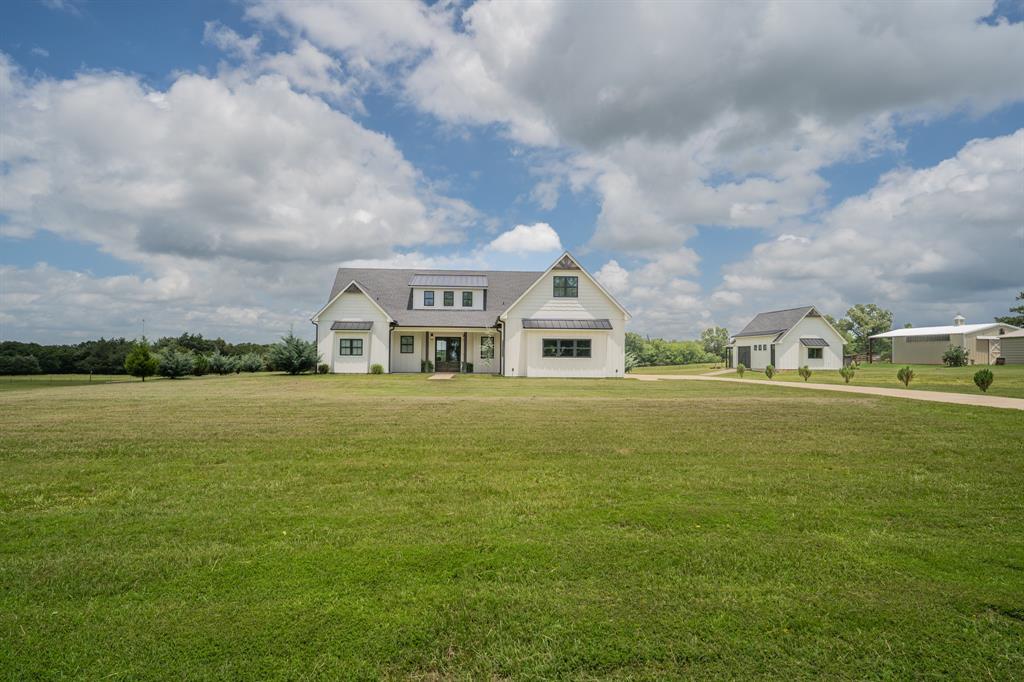 Minutes from the Sulphur Springs Country Club, this stunning 4-bed, 3.5 bath, 2 living rooms, and office is a sophisticated farmhouse chic design, sitting on two acres. Inside, you'll enjoy a seamless balance of grandeur with everyday functionality. Elegant, durable luxury vinyl plank flooring flows seamlessly throughout the house. The open floor plan showcases a show-stopping, white-and-bright chef’s kitchen. This culinary masterpiece features custom cabinetry, sleek granite countertops, a massive center island, and a ZLINE double oven range with a 6-burner gas cooktop. The kitchen opens beautifully to the main living area, where a cozy, floor-to-ceiling stone fireplace with gas logs serves as the perfect focal point for gatherings. Designed with unparalleled versatility for multi-generational living, upscale entertaining or a large family, the layout boasts two separate, living areas and two true primary suites. The downstairs primary serves as a private oasis, complete with a double vanity, a deep soaking tub, a separate walk-in shower, and a massive walk-in closet outfitted with custom built-in cabinets, while the upstairs primary offers a second private retreat with excellent separation of space. In addition, you'll also find an office and a laundry room with custom built-ins and sink including access to the back porch. Outdoors, the large covered back patio provides an ideal canvas for open-air dining and relaxation. A versatile workshop offers space for hobbies, projects, and a well-thought place for pets off the back. Take advantage of scenic country living while still close to town and zoned for the brand new Rowena Johnson Elementary.